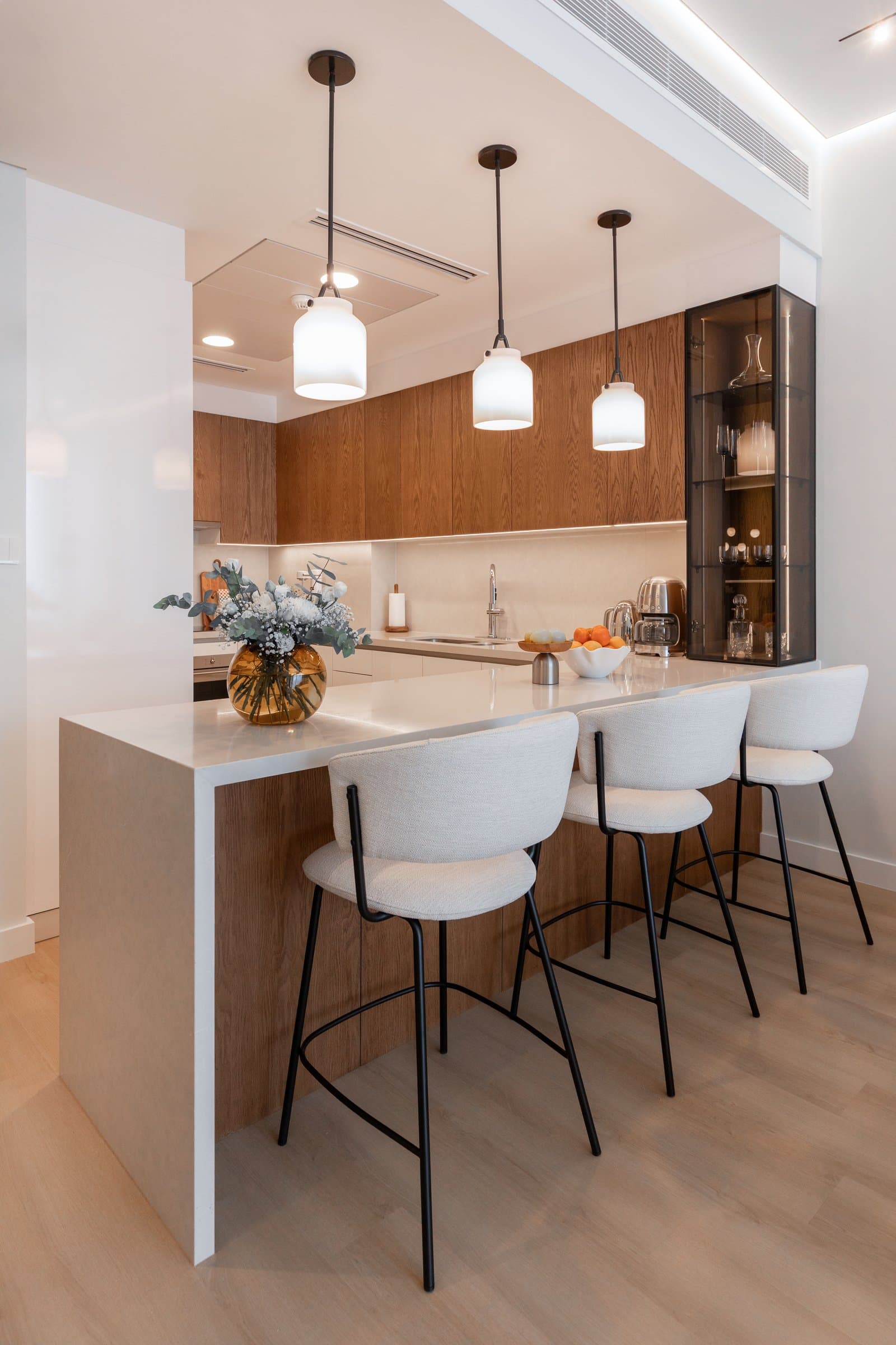 Three milk-glass pendants provide the only graphic line in an otherwise rounded kitchen composition