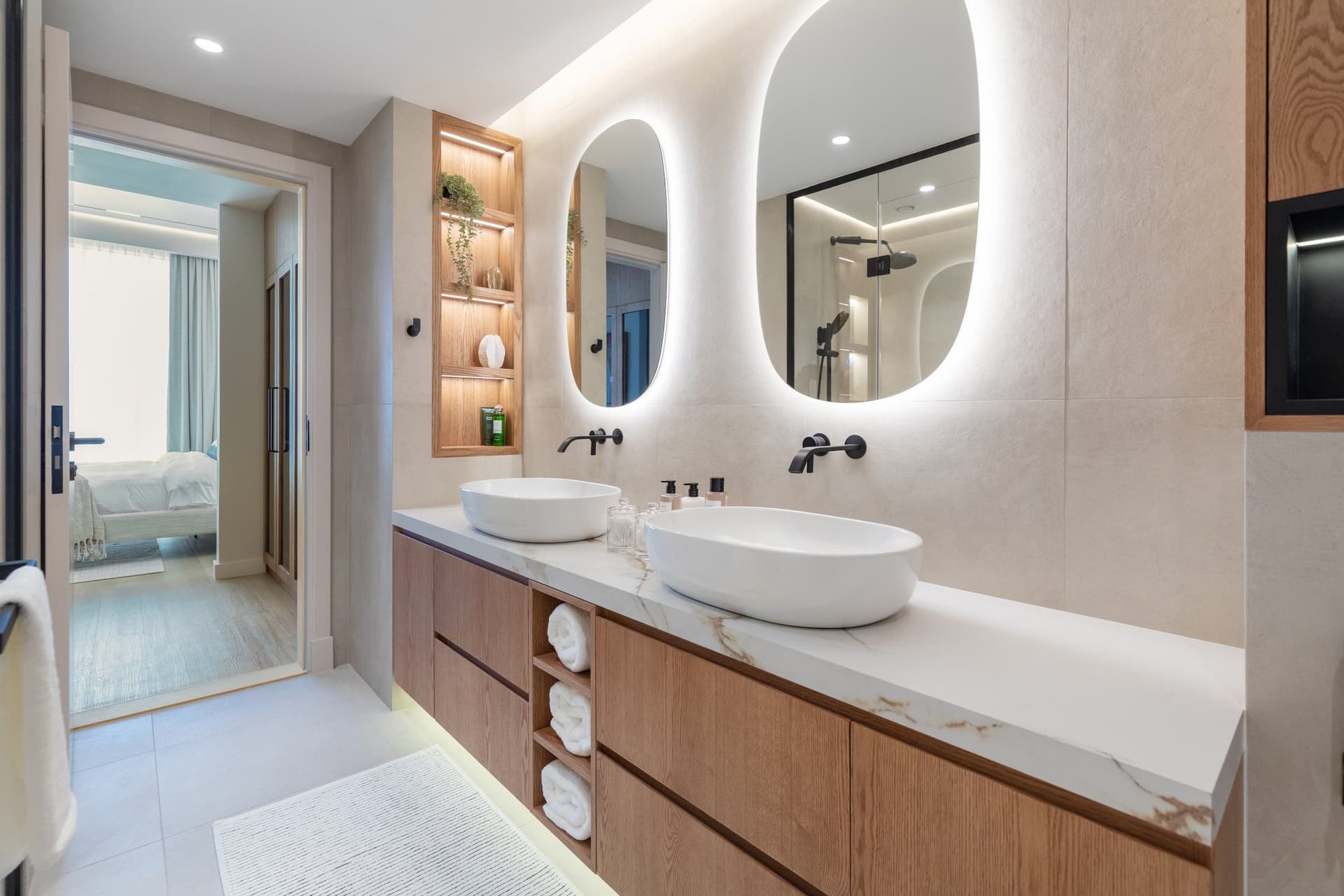 Twin oval mirrors with halo backlighting float above a calacatta-veined vanity