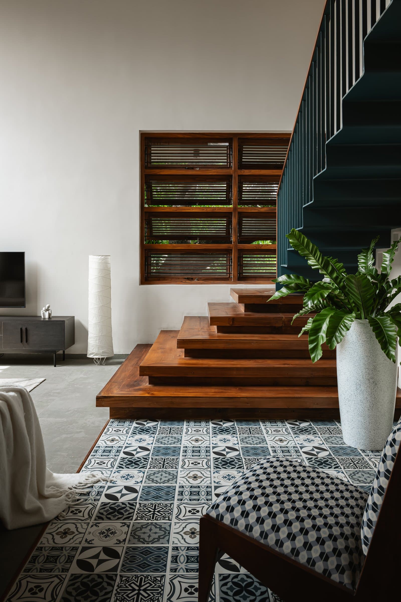 The base of the staircase doubles as informal seating, with the encaustic tile floor performing its quiet ordering work