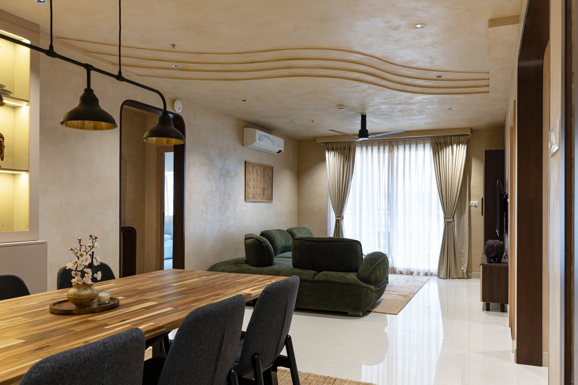 The drawing-and-dining volume, unified beneath a wave-textured ceiling that runs the room's full length