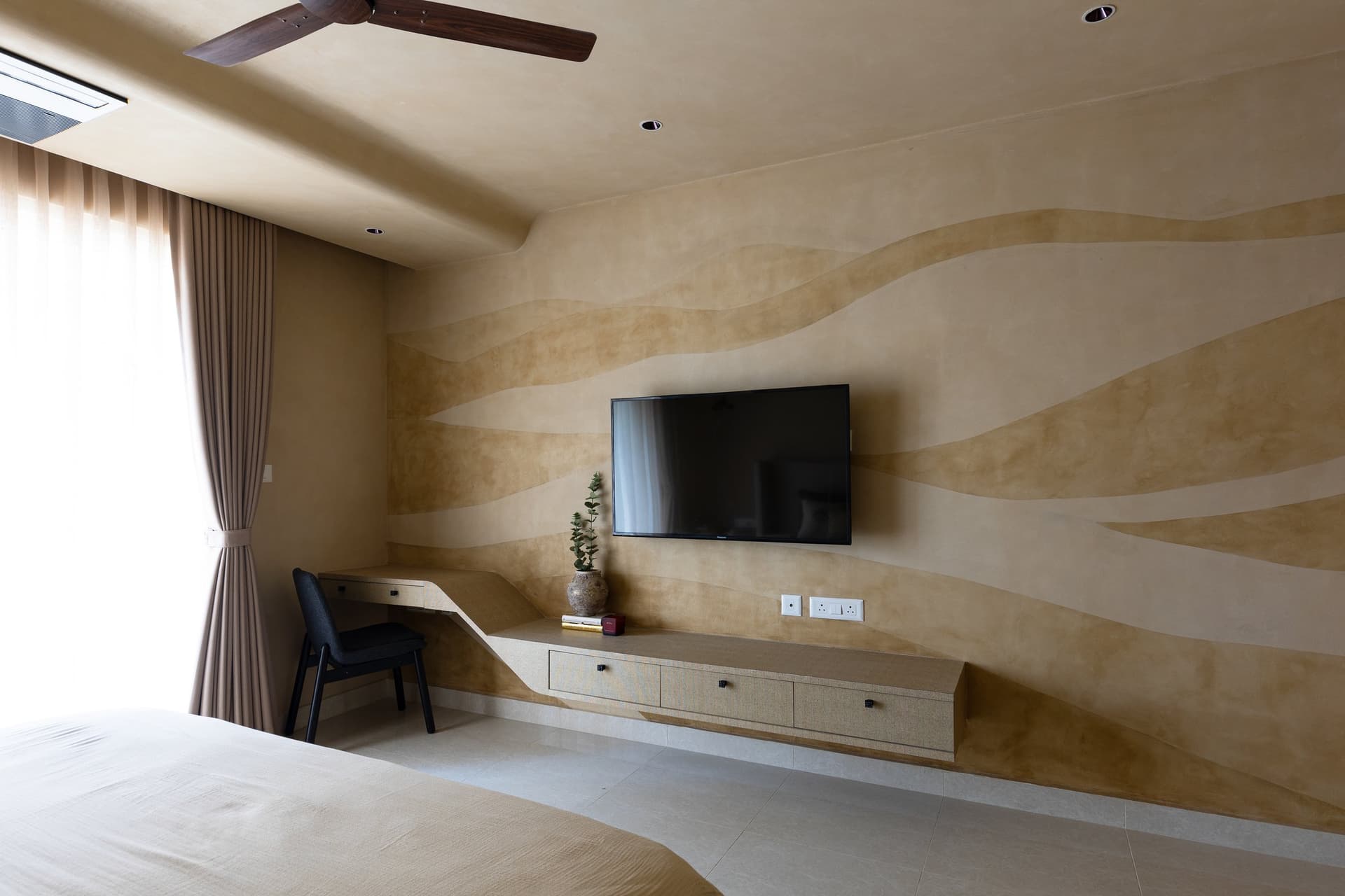 The hand-rendered limewash mural opposite the bed, with a floating cane-grain console running its full length
