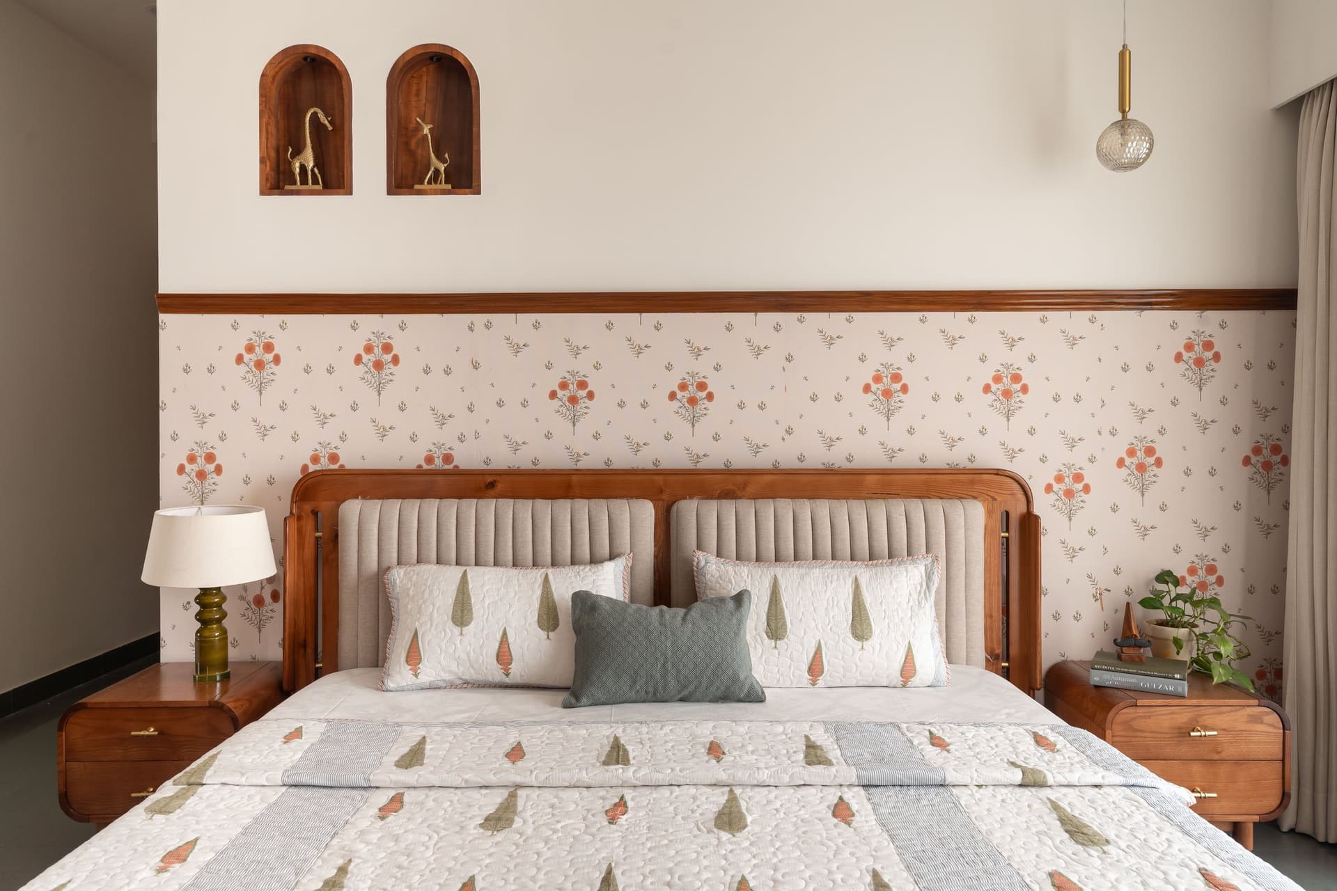 The master bedroom, where orange-blossom wallpaper meets twin arched niches holding brass giraffes