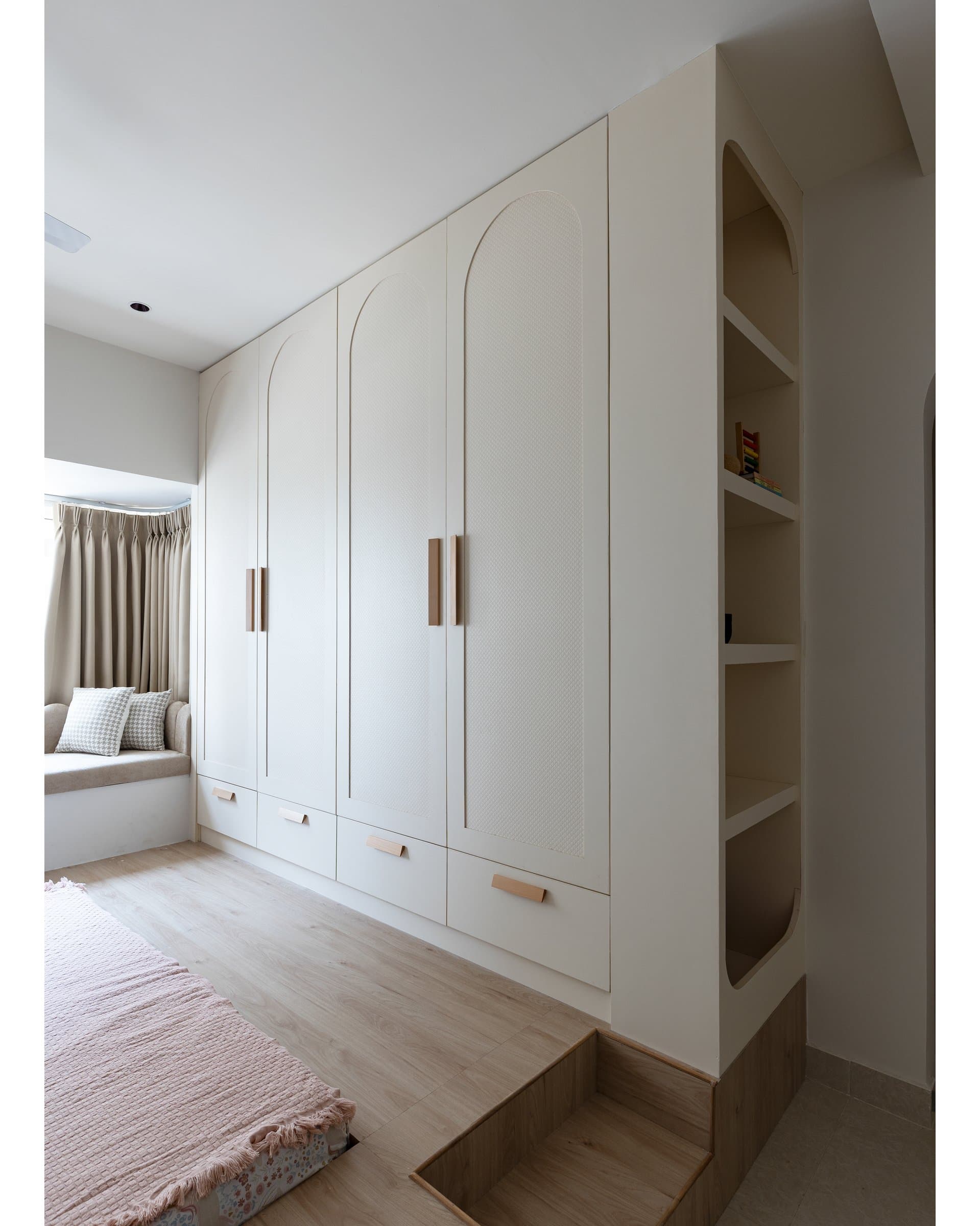 Arch-detailed wardrobes in chalky off-white, with leather pull-tabs as the only visible hardware