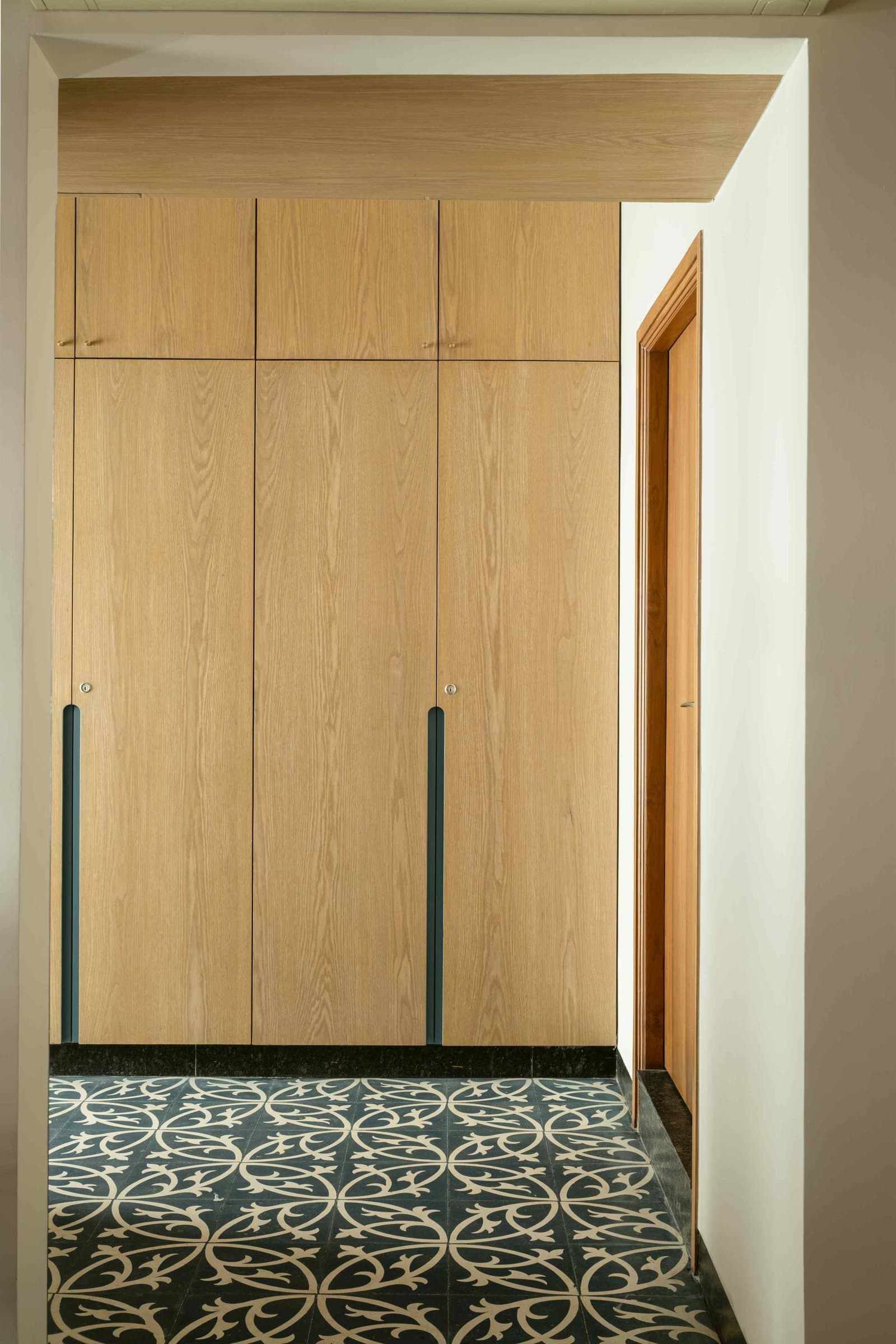 A dressing alcove where pale-oak millwork meets a contemporary reading of traditional cement tile