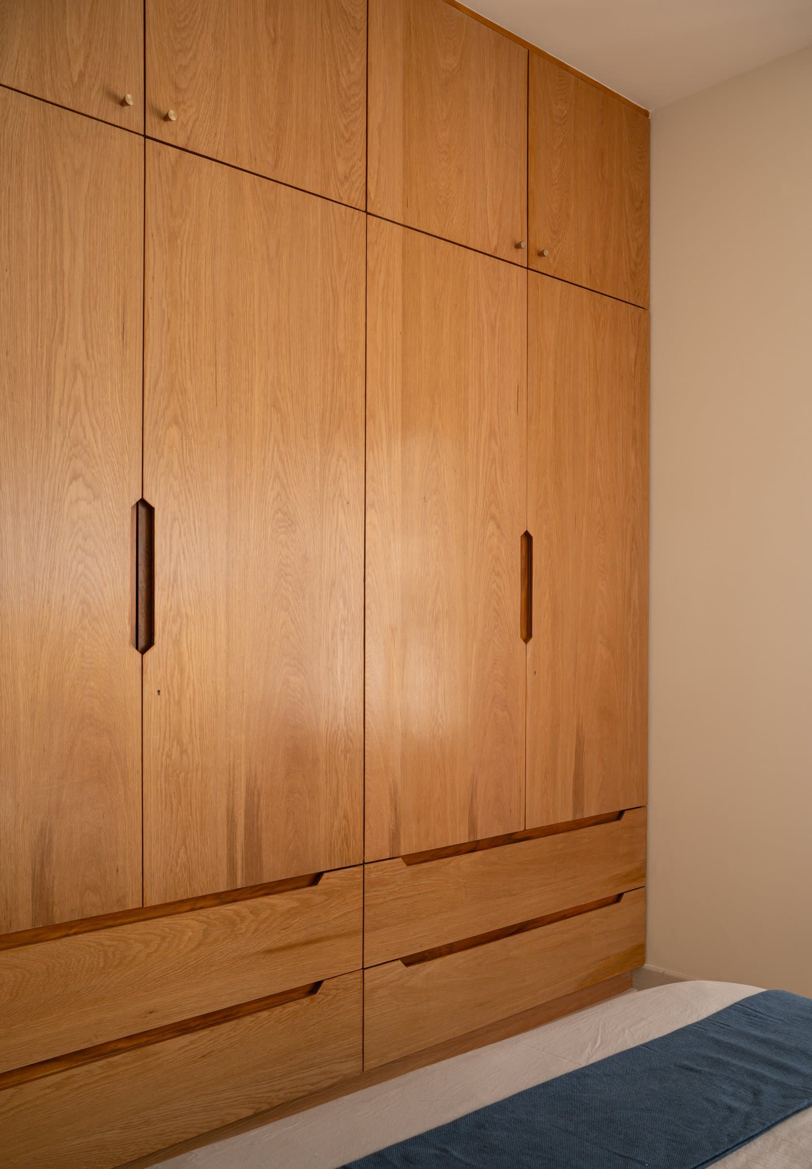 The master wardrobe spans a full wall in clean wood-grain panels, its capacity absorbed almost invisibly into the architecture