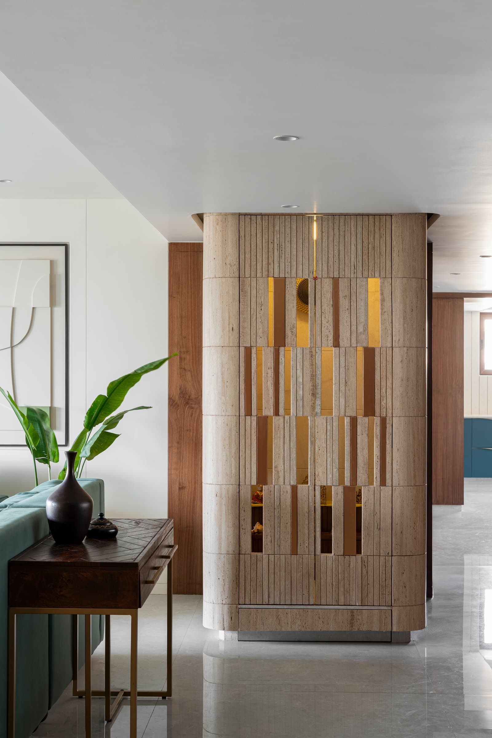 The temple, a sculpted travertine column with brass-lined inserts, stands as the home's luminous centrepiece