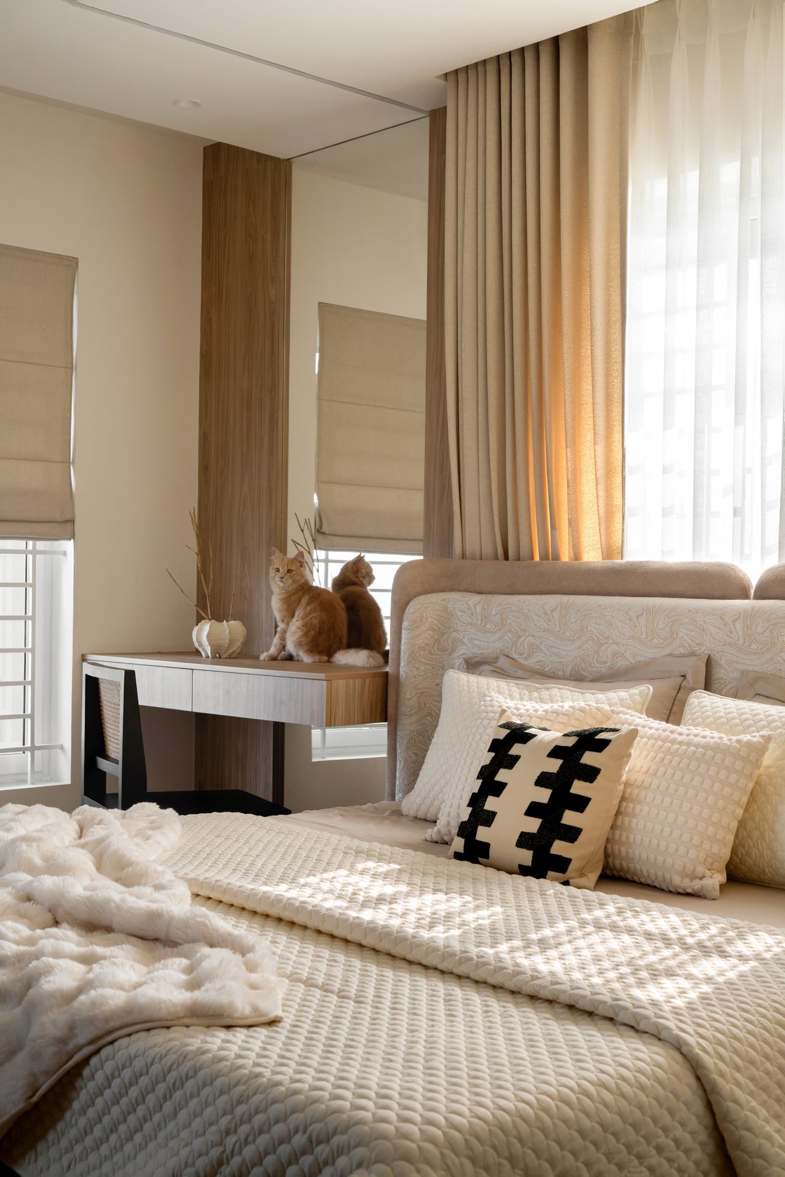 The dressing console alongside the bed, with linen Roman shades tempering the light