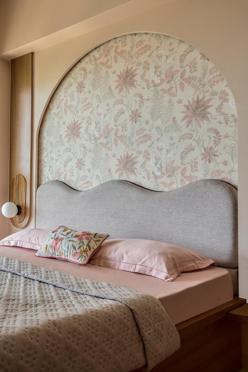 The master bedroom, where a curved arched panel layers botanical wallpaper over a wave-edged upholstered headboard