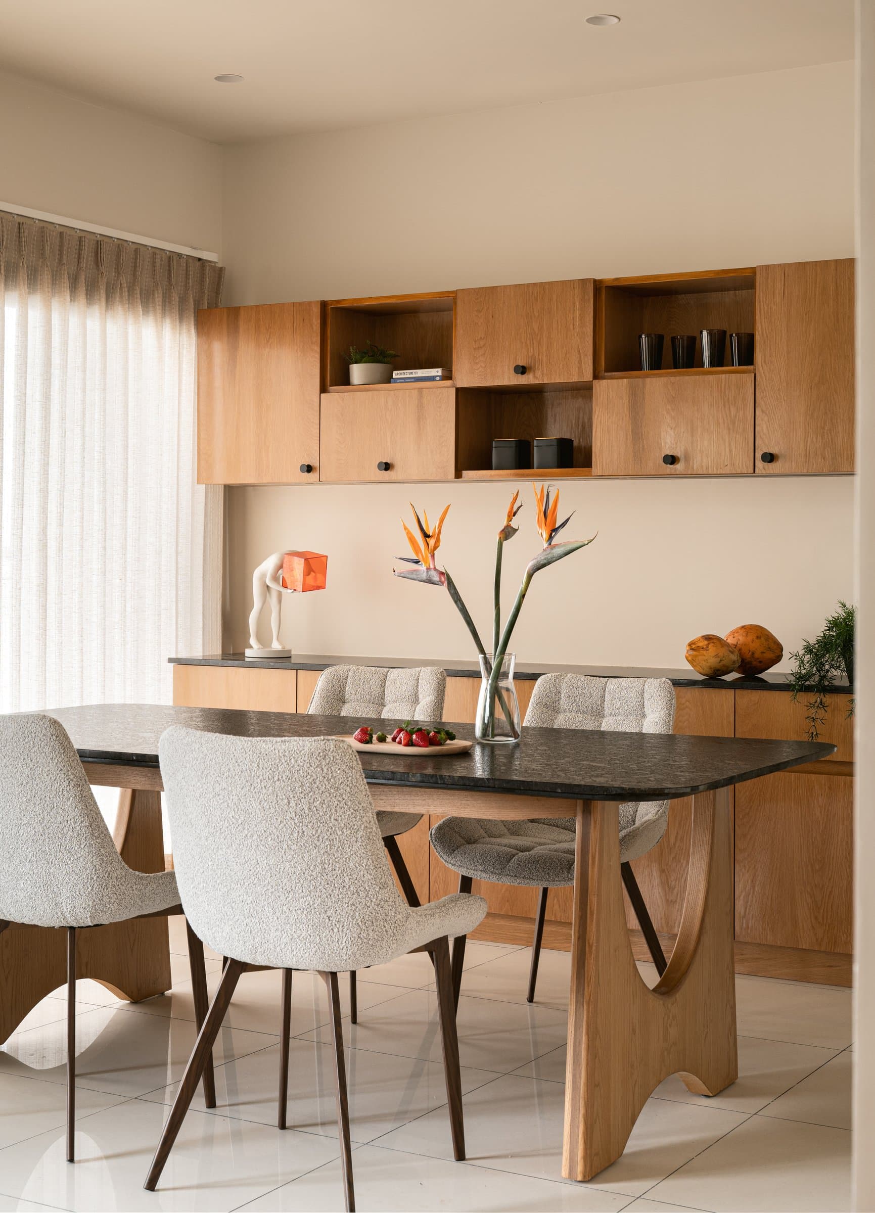The dining area, where a black stone-topped table on a sculptural wood base anchors an otherwise restrained palette