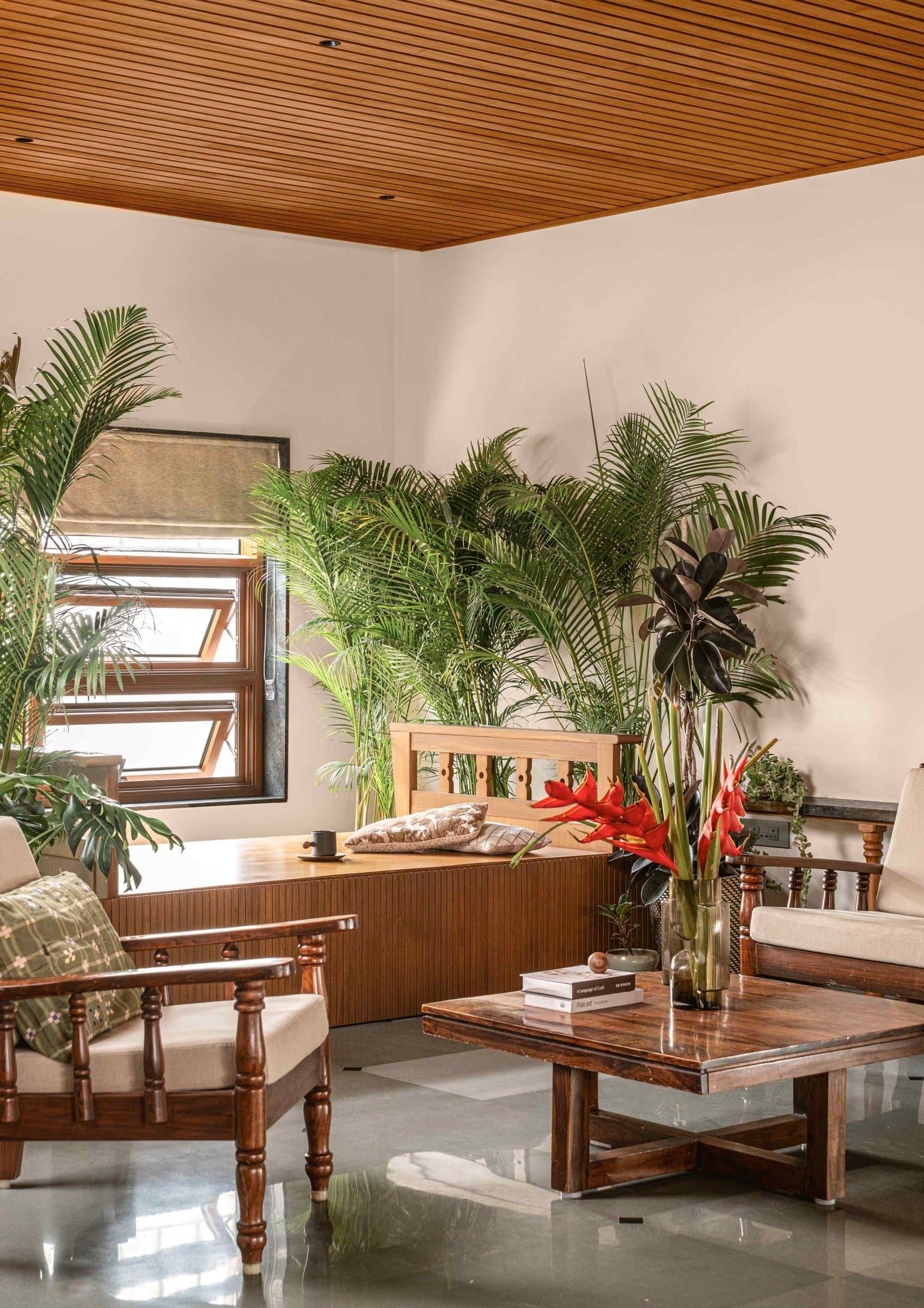 The living room treats greenery as architecture, with a built-in daybed framed by towering areca palms