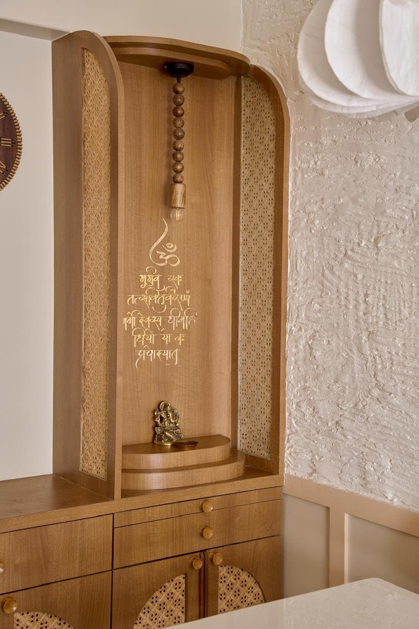 The built-in pooja niche, framed in cane and carrying a gilt-inscribed Sanskrit shloka