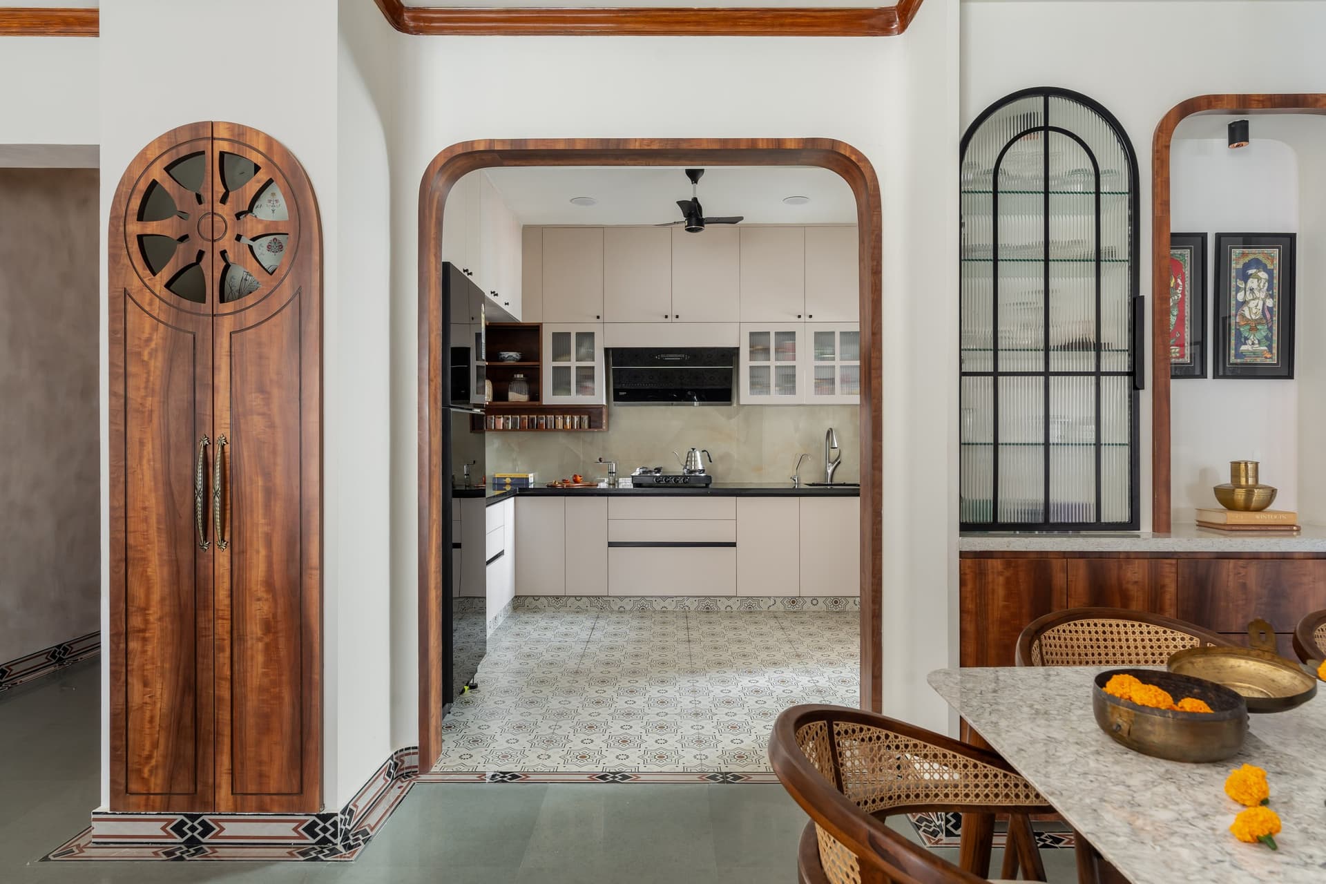 The teakwood archway between dining and kitchen, flanked by a Konark Chakra cabinet that translates temple iconography into joinery
