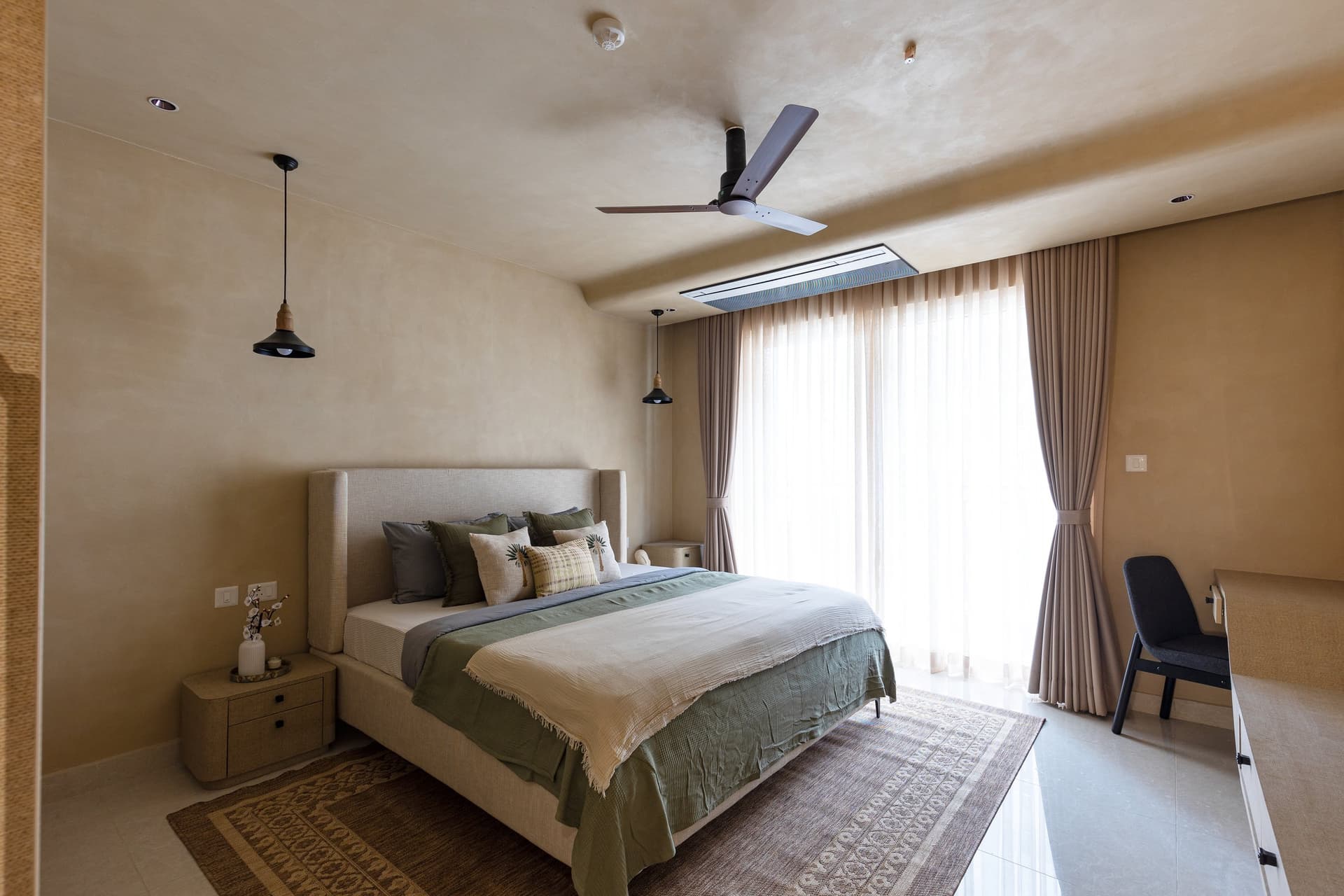 The master bedroom in deeper limewash tones, with low pendants standing in for conventional bedside lamps