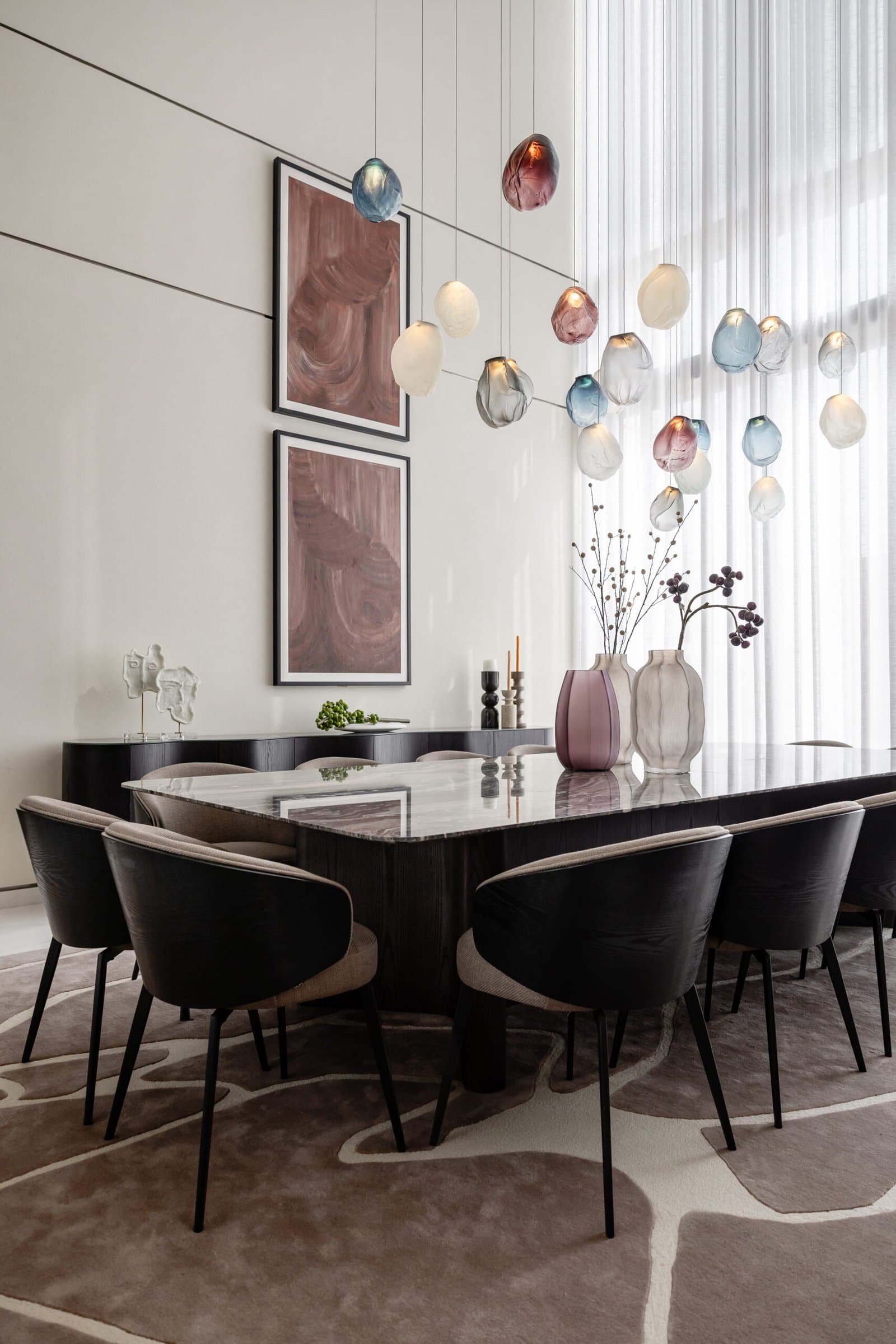 The dining room, where a constellation of dusky-toned glass pendants cascades above a stone-topped table