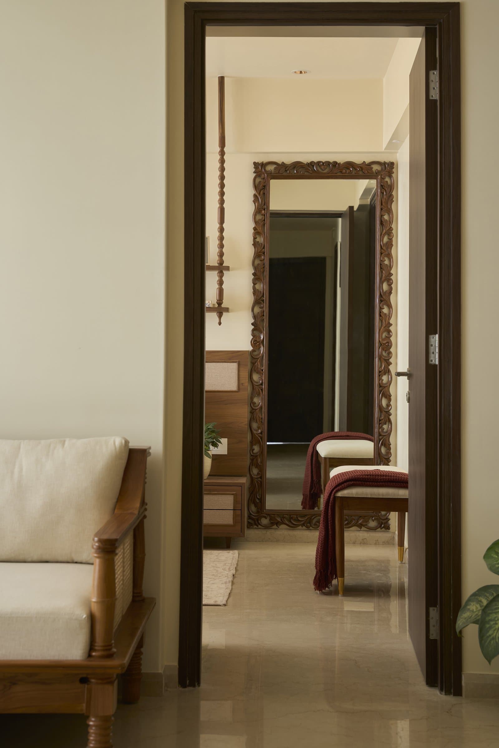 The passage to the master bedroom, where a carved wood mirror extends the home's linear axis and doubles the available light