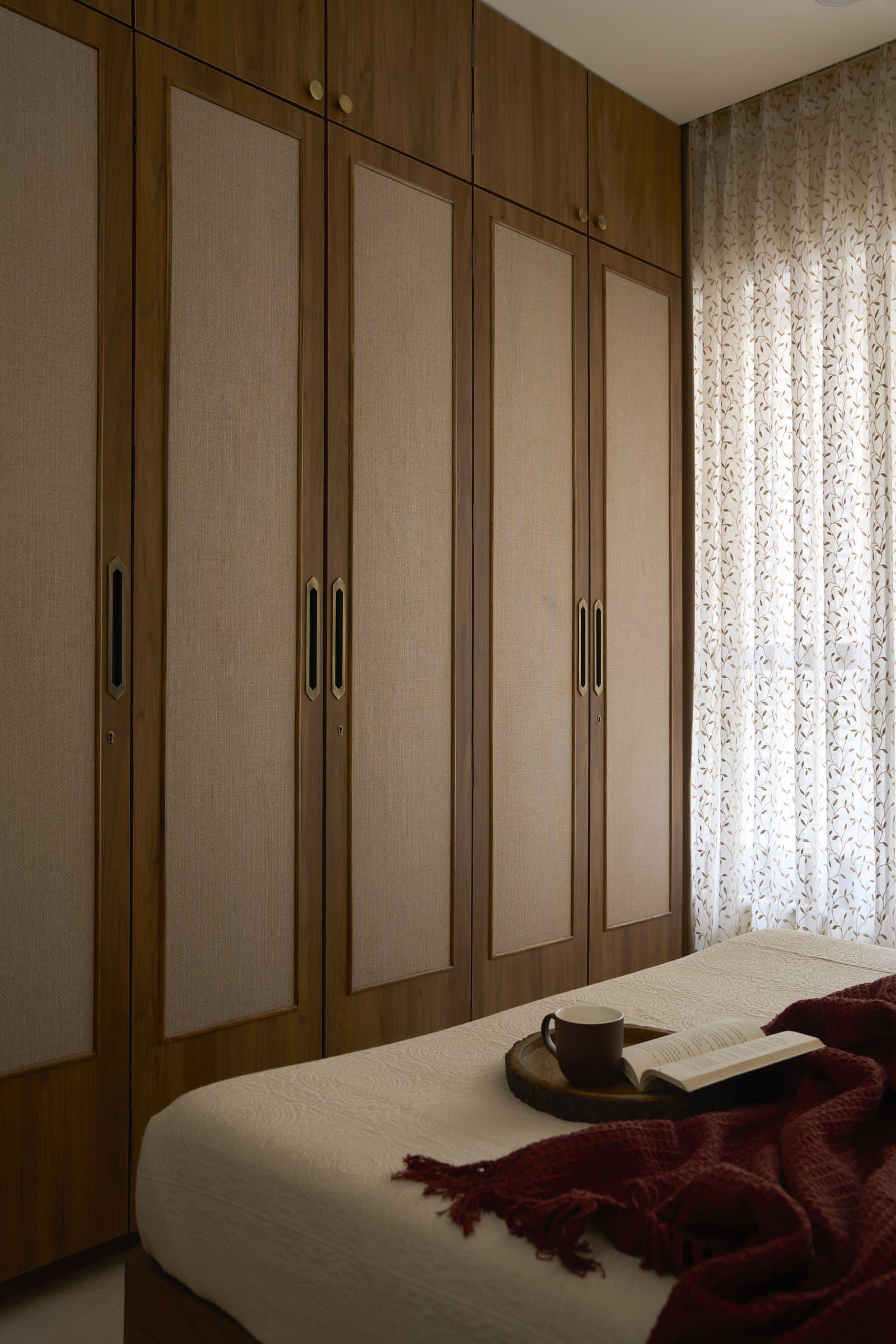 The wardrobe wall, where jute panels set within wood frames keep a uniform façade from reading as monolithic