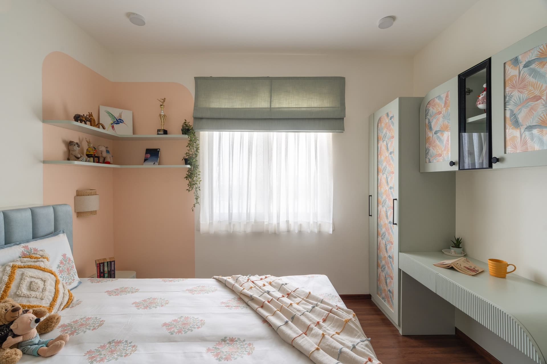 The daughter's bedroom, where a curved peach feature wall holds shelves of small personal treasures