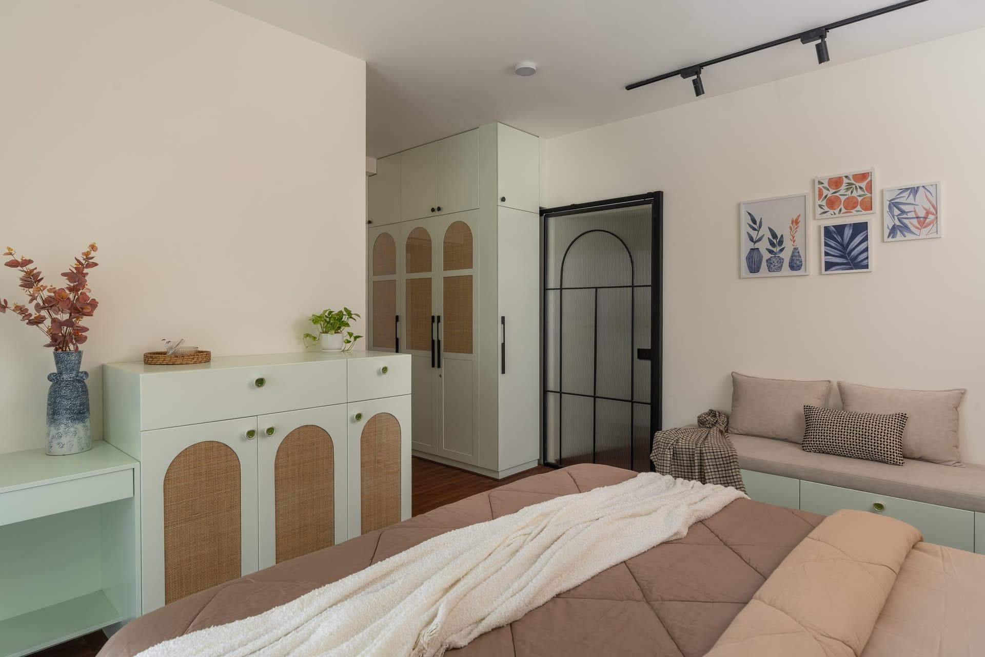 The opposite side of the master bedroom, with sage cane-fronted joinery and a fluted-glass en-suite door