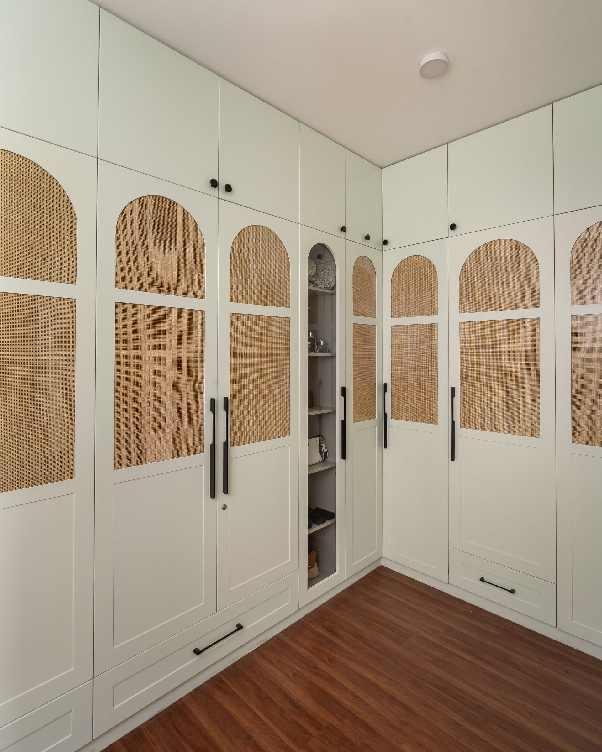 The walk-in wardrobe, where arched cane inserts repeated across every door turn storage into architecture