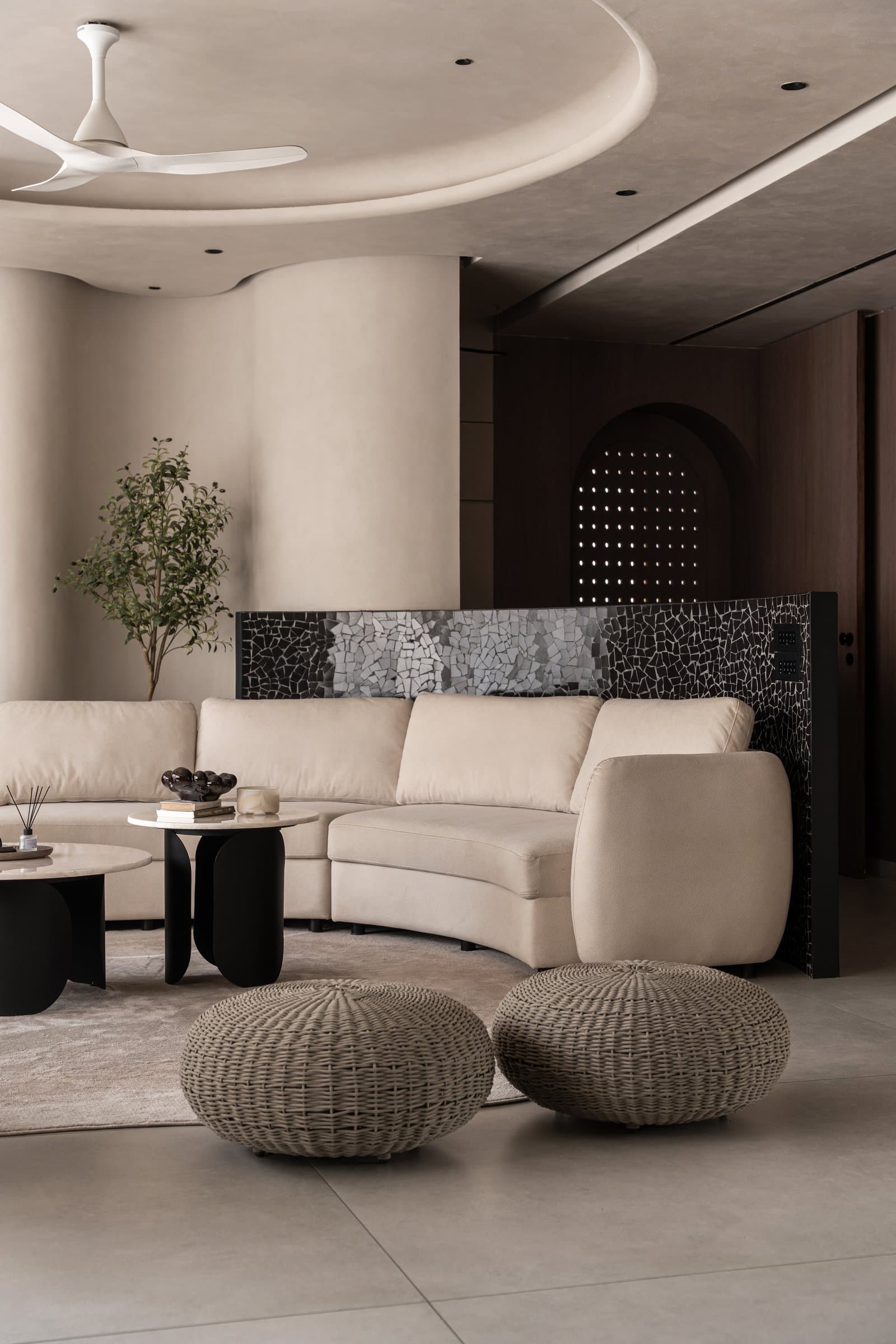 The mosaic screen behind the sectional, the room's one note of deliberate grit against an otherwise softened palette