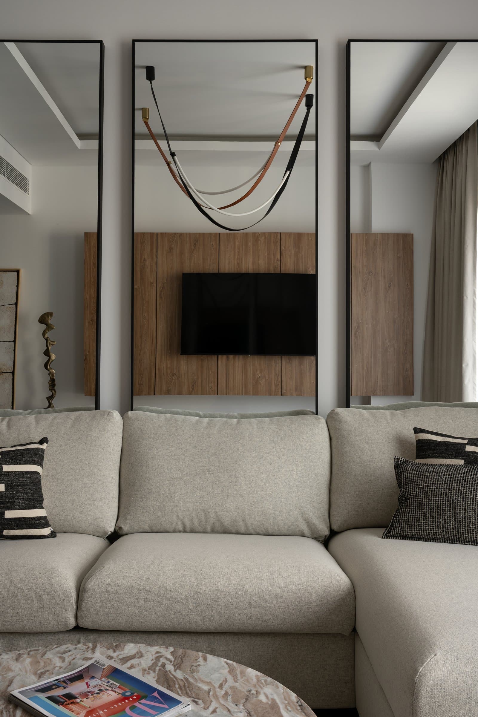 Twin black-framed mirrors flank the sectional, holding the composition in loose symmetry