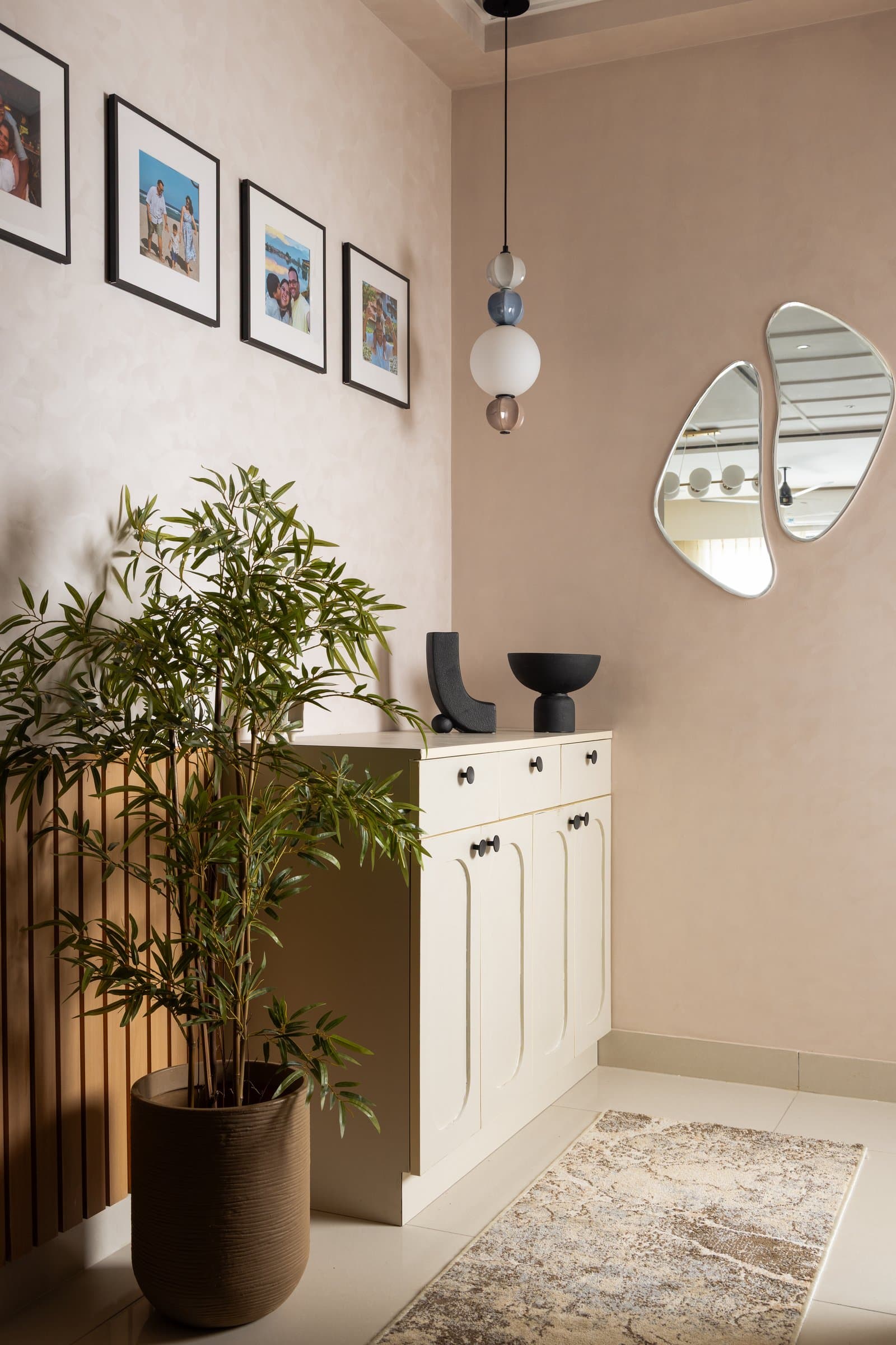 The foyer: a blush textured wall, slatted wood screen and arched-panel cabinet establish a soft, considered threshold