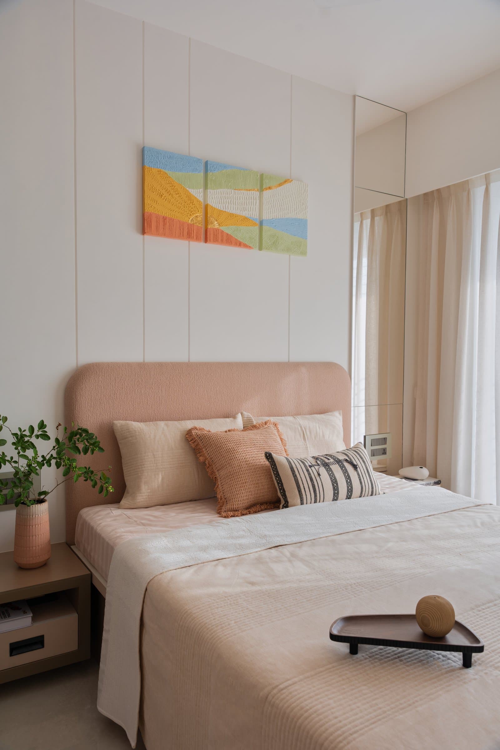 The guest bedroom, organised around a peach headboard and a triptych of textured artworks