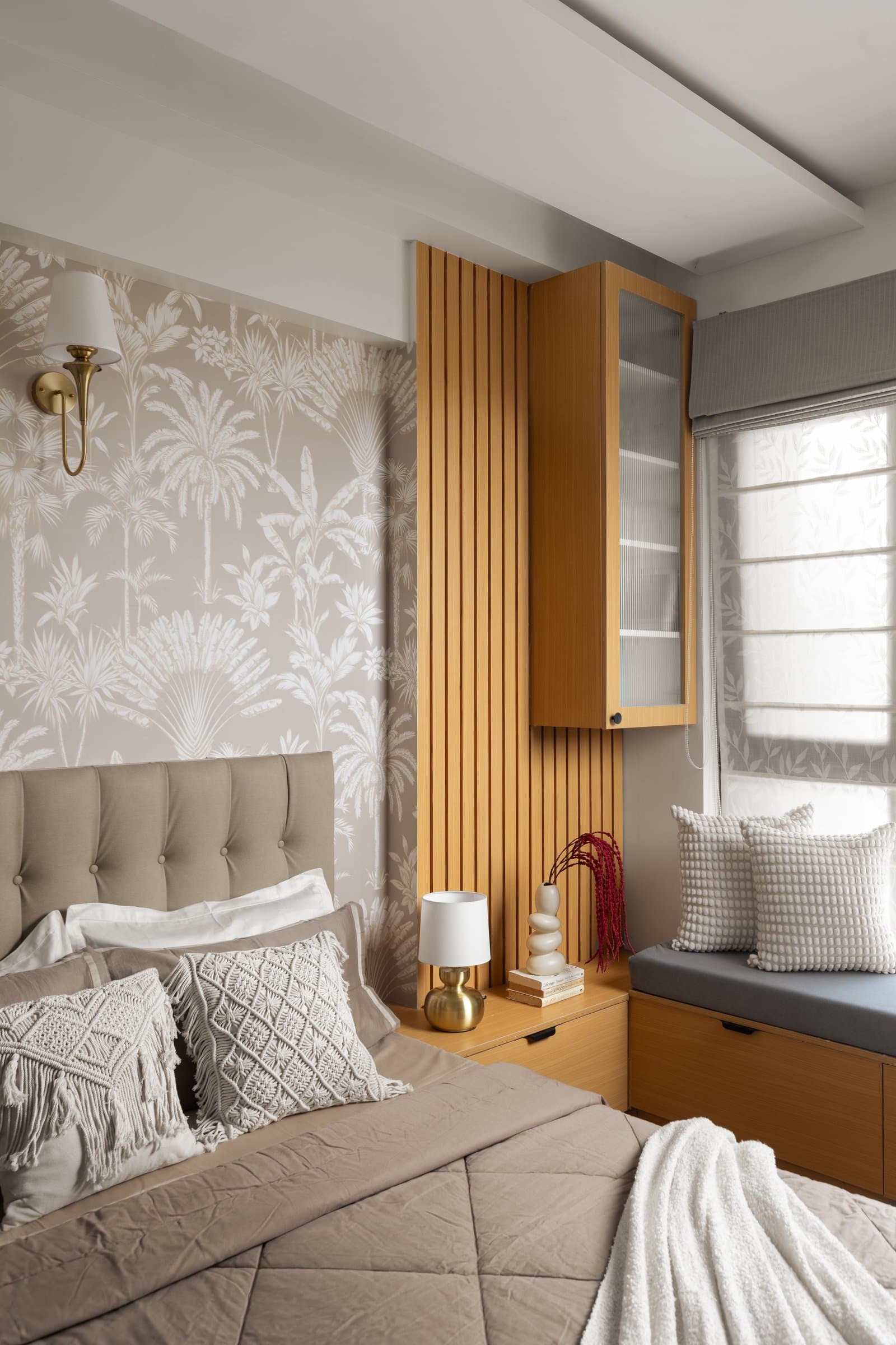 The guest bedroom opens with a tufted headboard, palm-print wallpaper and a wood-clad window seat