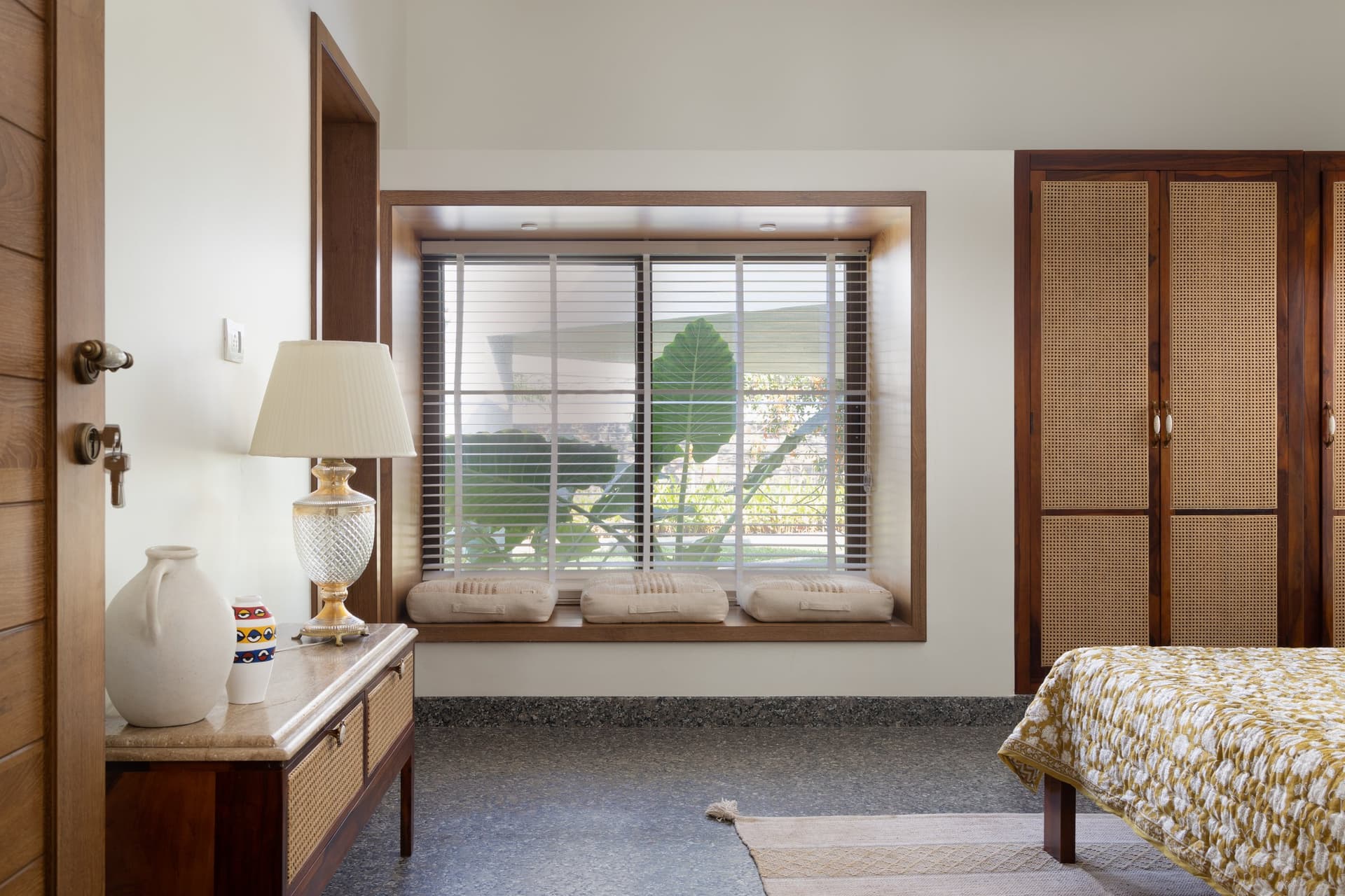 The third bedroom treats its box-window as furniture, with three linen cushions facing the garden through slatted blinds