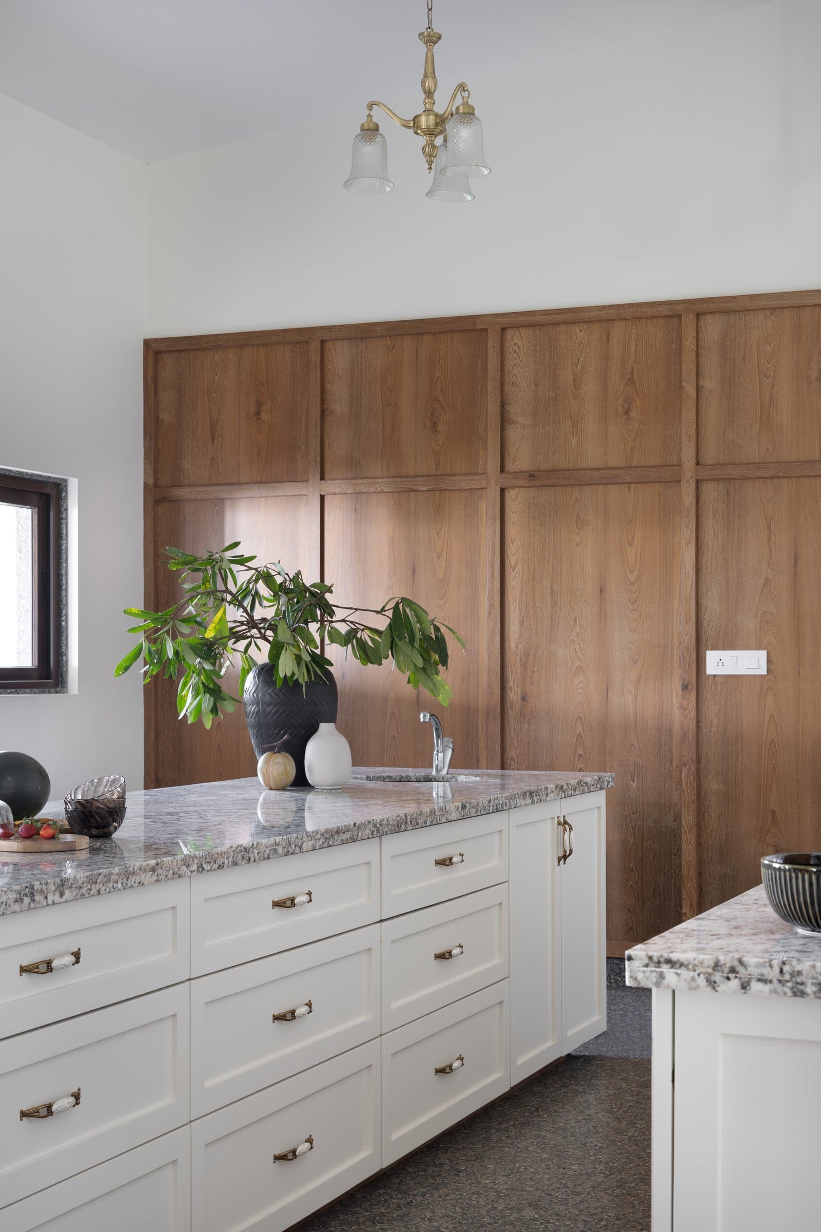 A full-height wall of vertically-stacked wooden panelling pulls the kitchen's centre of gravity toward warmth
