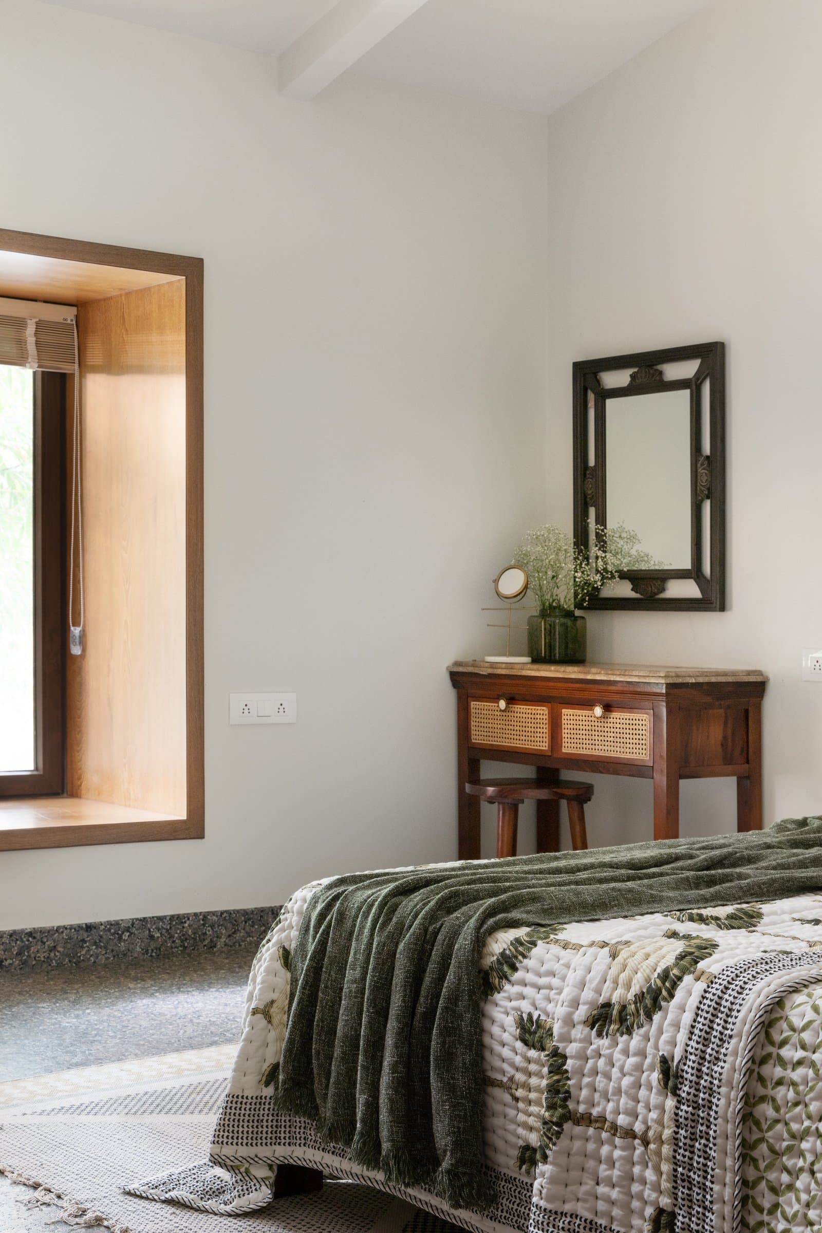In the second bedroom, a caned writing console and carved mirror sit below a deep wooden window reveal