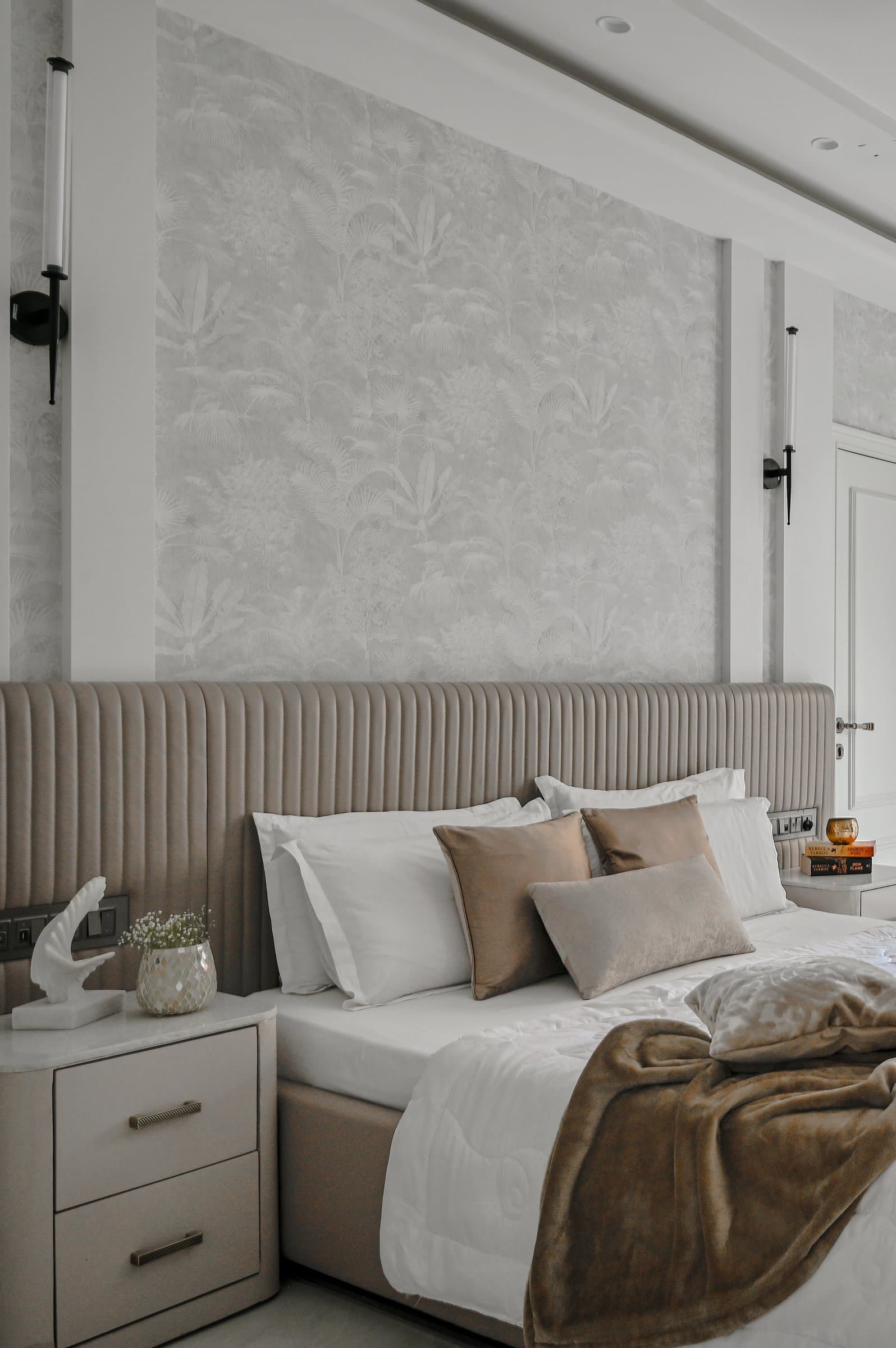 The second bedroom, warmer and more atmospheric, leans into honeyed bronze and botanical wallpaper