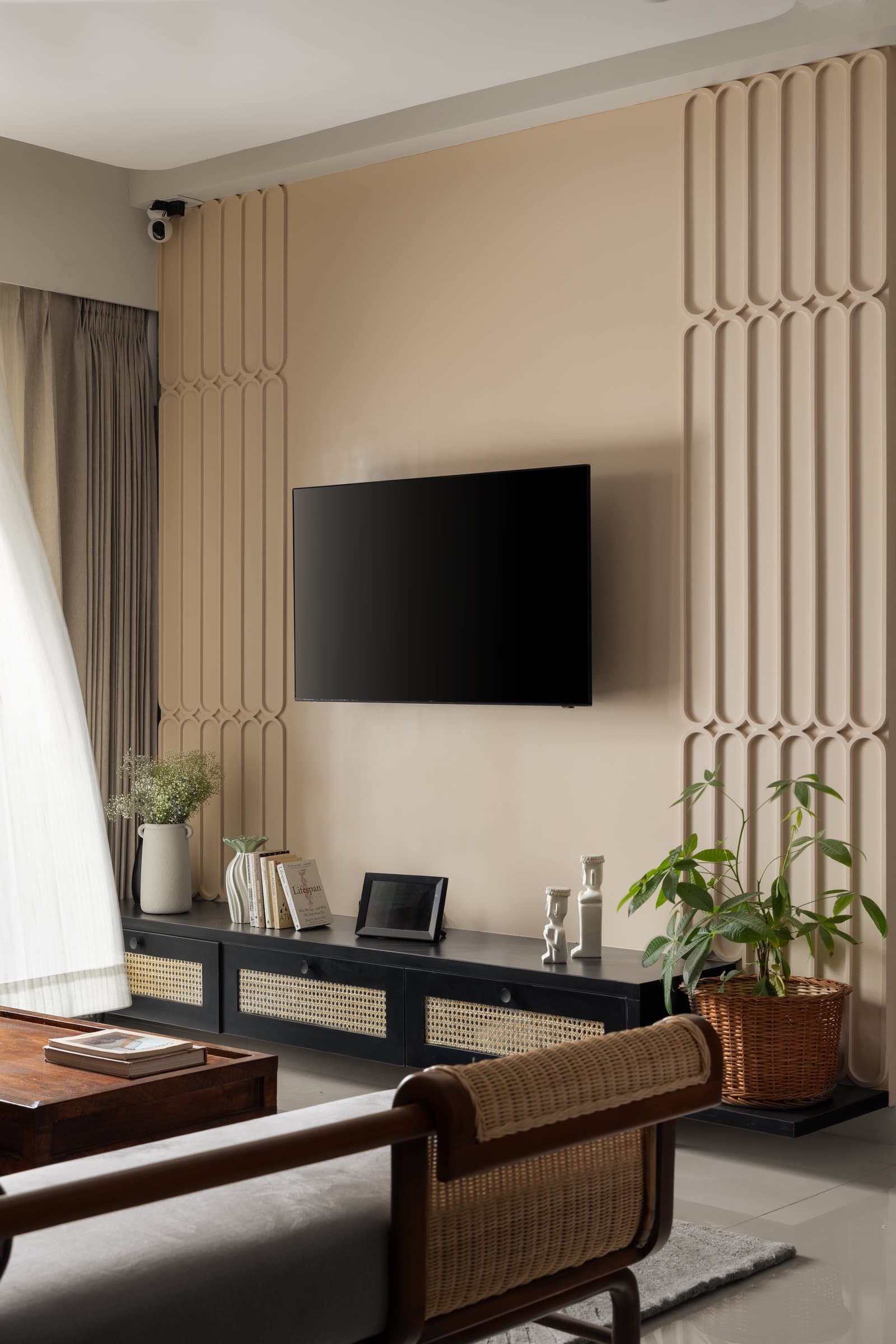 The television wall, dignified by elongated arched mouldings and a cane-fronted console below