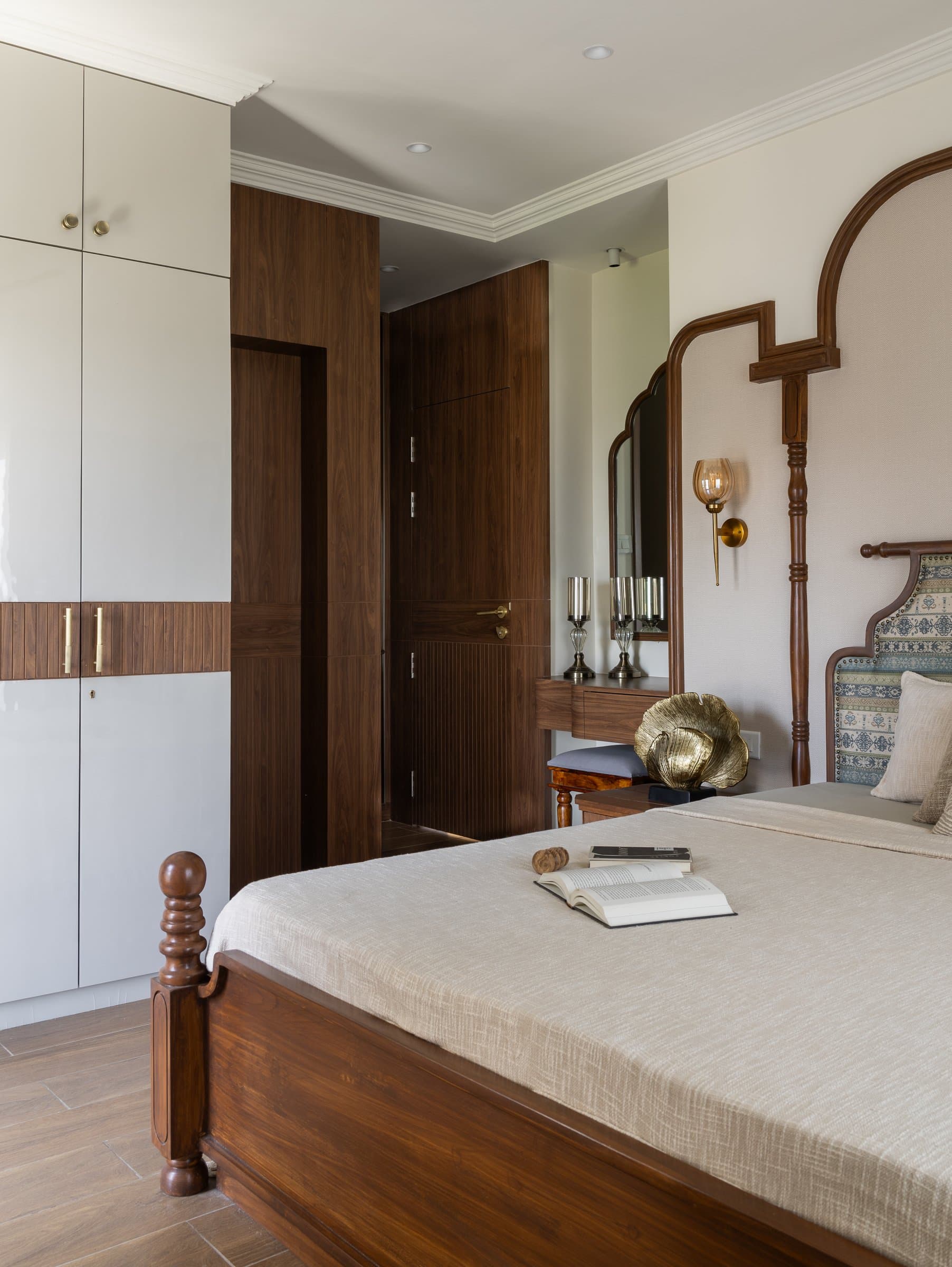 The master bedroom, where a four-poster wooden bed sits within a stepped wooden moulding traced around an upholstered headboard