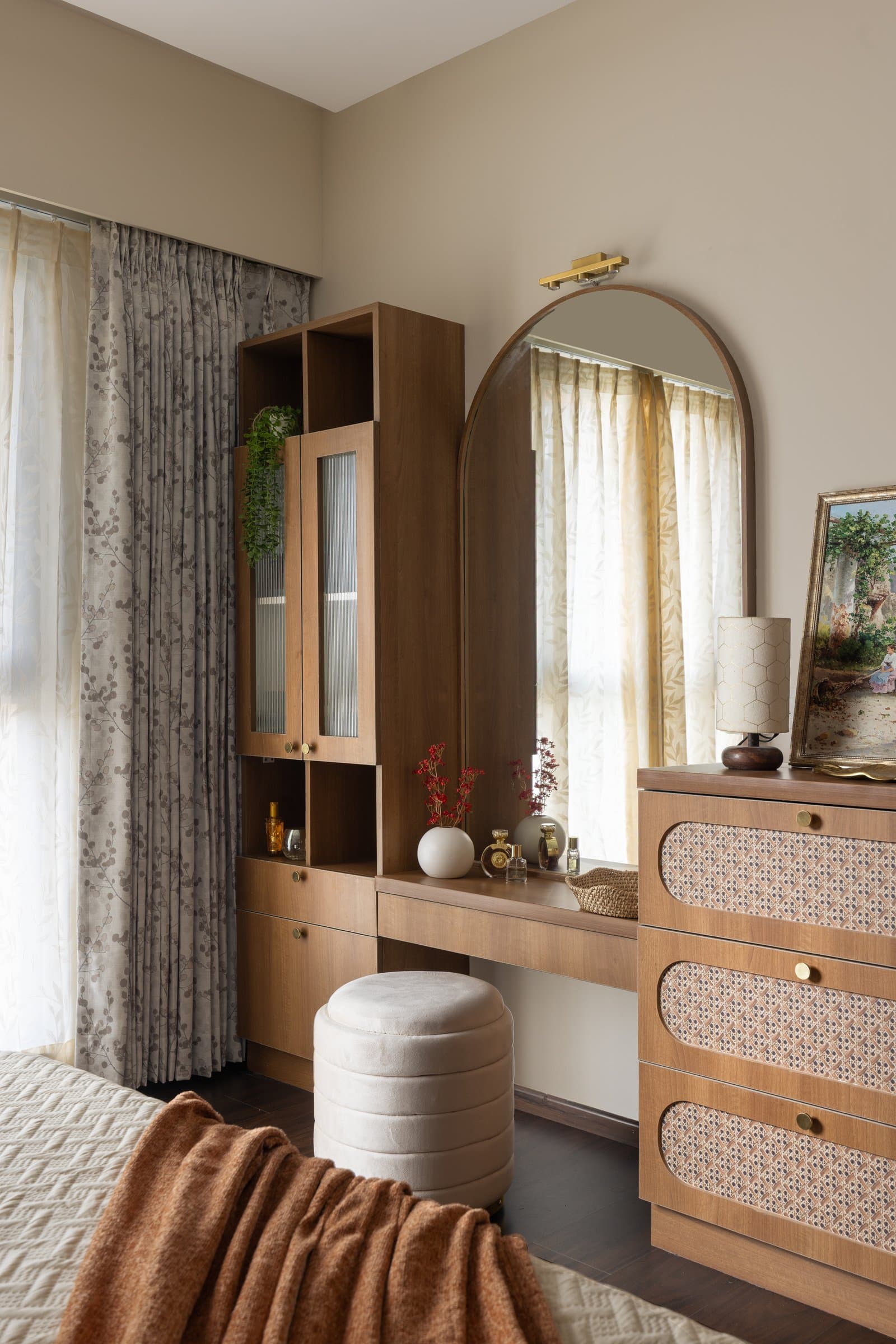 The dressing unit: an arched mirror, cane-panelled drawers and a honeycomb-shaded lamp anchor the bedroom's grooming corner