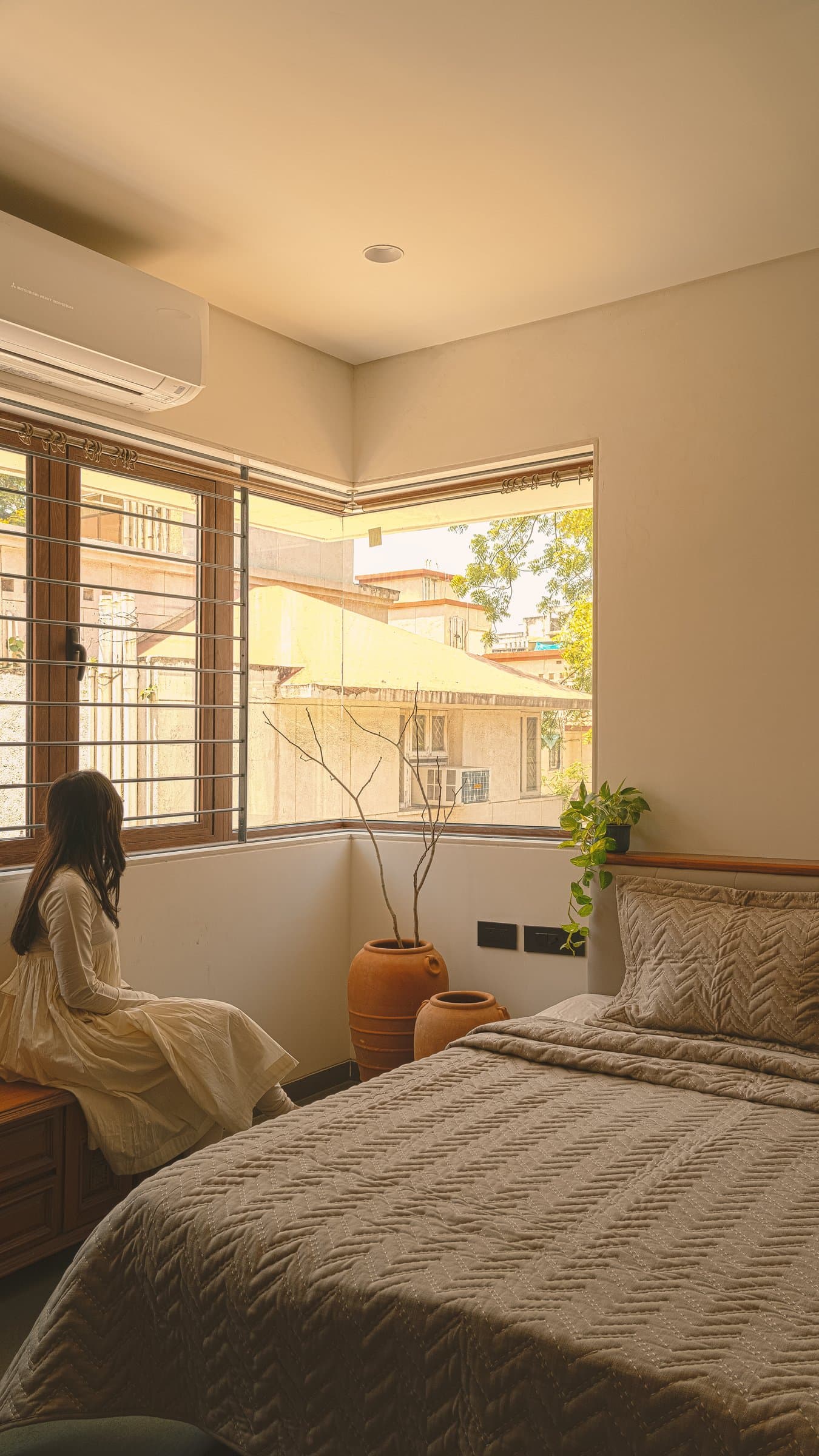 In the master bedroom, an L-shaped corner window pulls the canopy of the street into the room