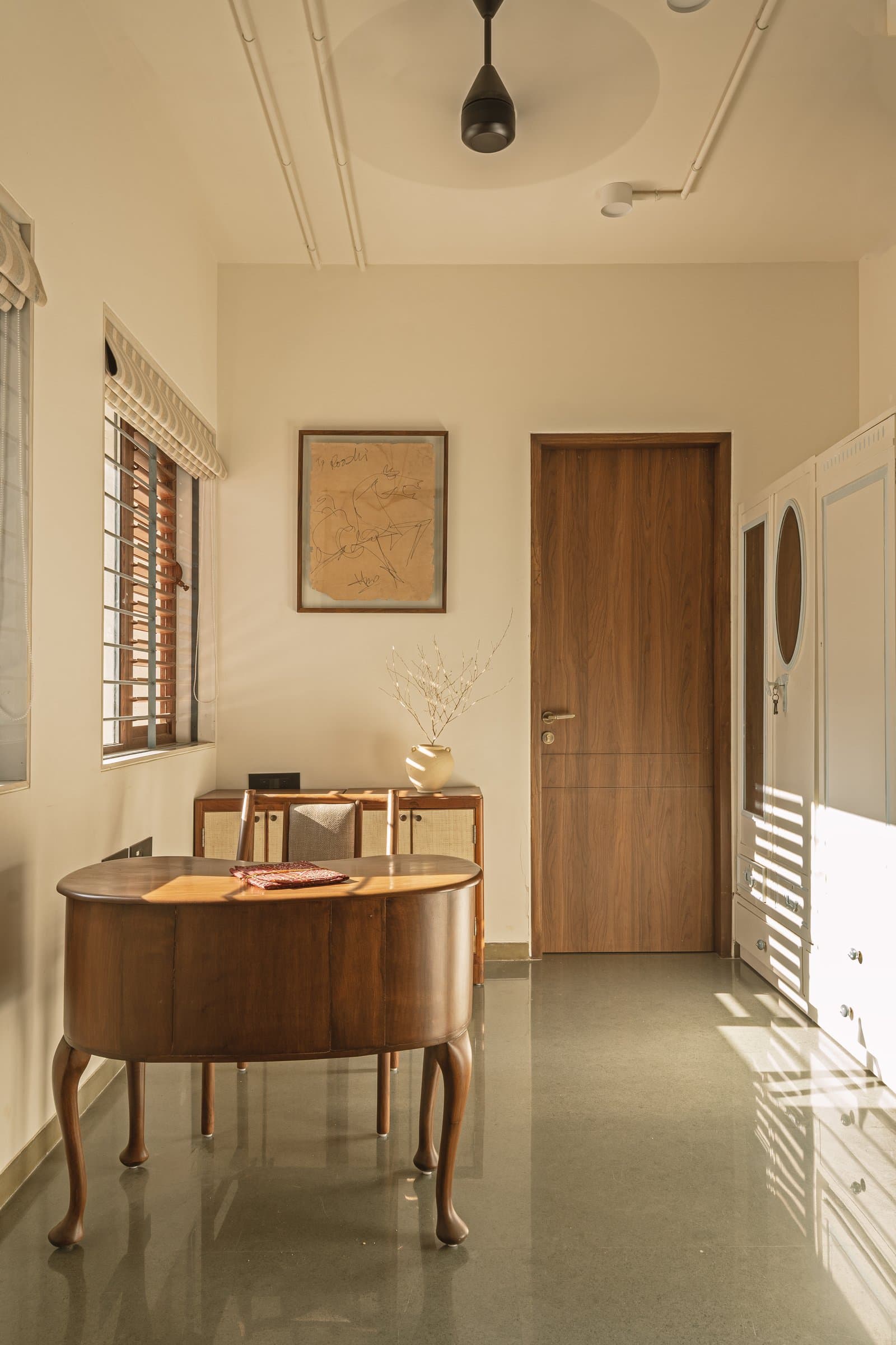 A sculptural desk on cabriole legs anchors the study room, the polished green floor stitching it back to the rest of the home
