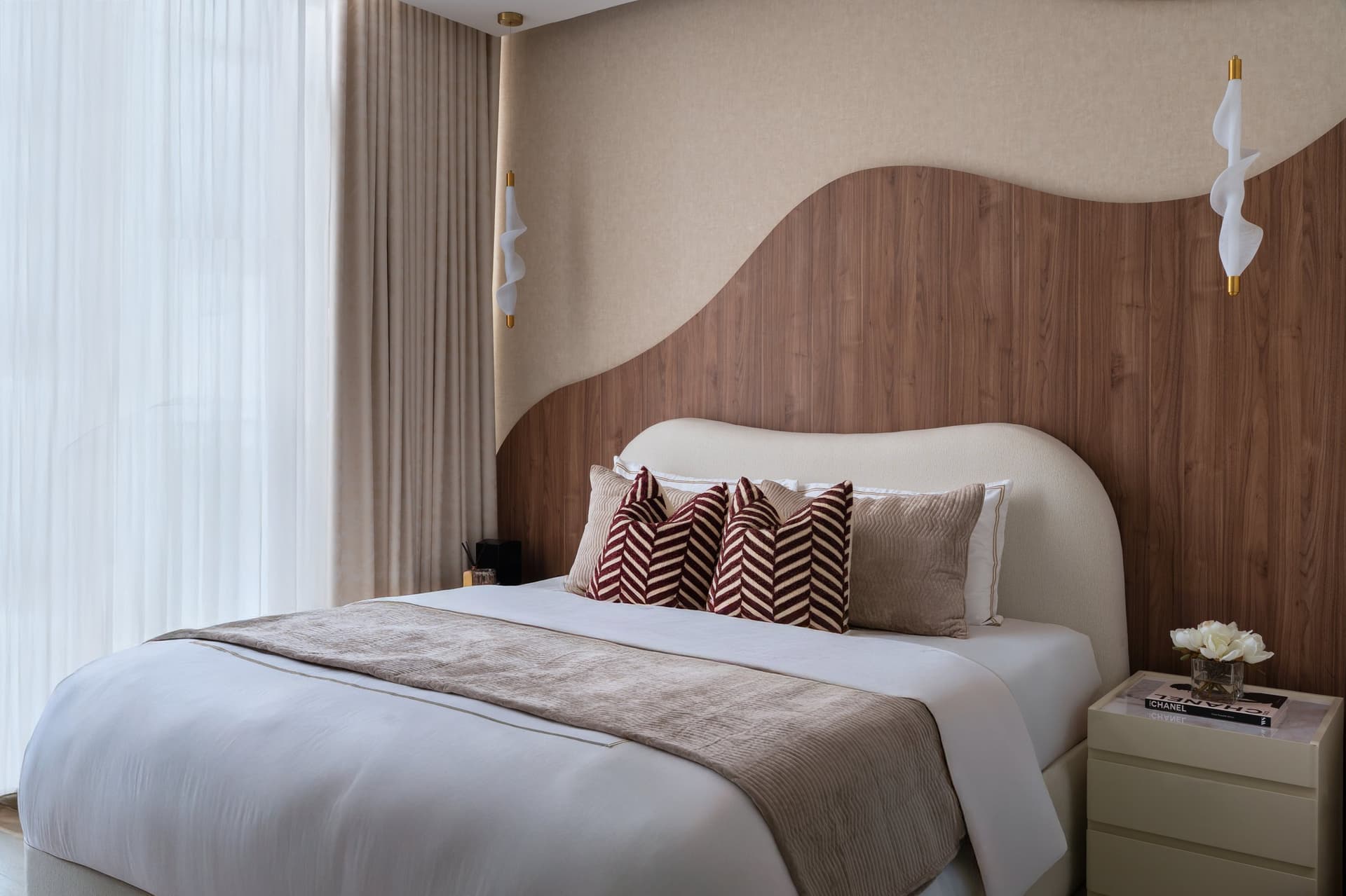 The master bedroom's headboard wall, a single composition of walnut and upholstered linen carved into wave-like forms