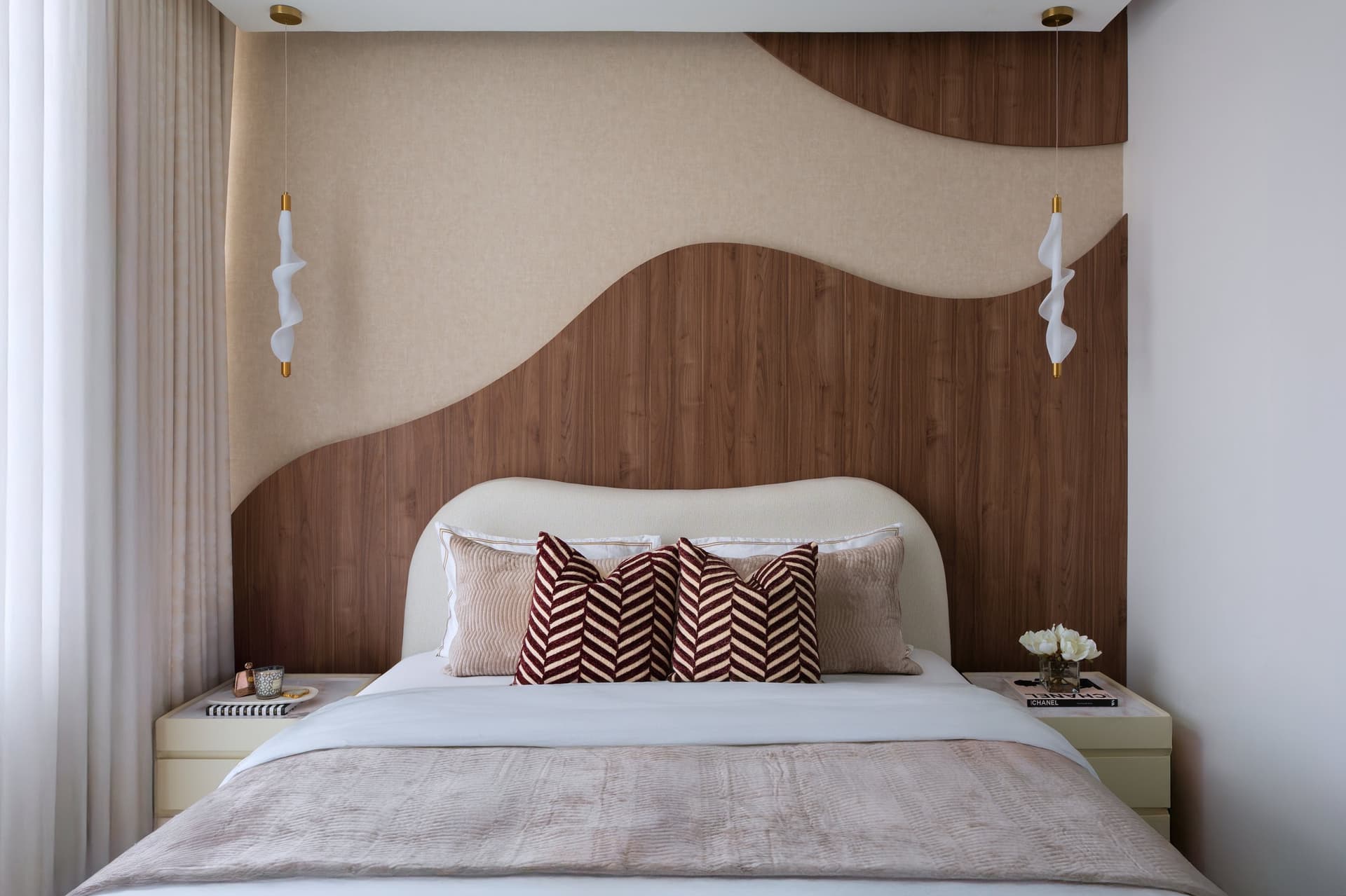 Seen head-on, the wall reads almost like a relief sculpture, with ribbon-form pendants flanking the bed in place of conventional sconces