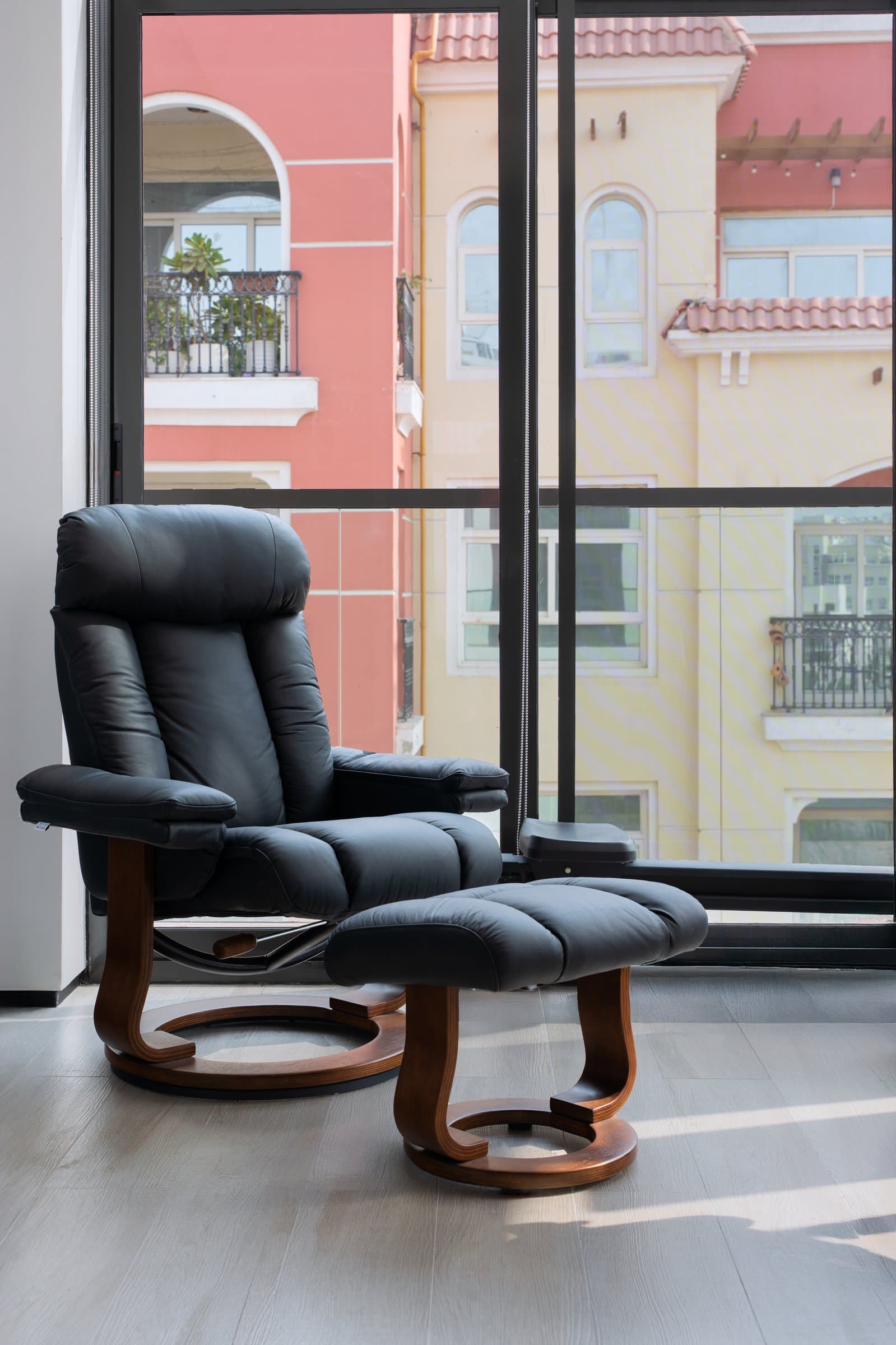 The recliner by the window, framing a view that is unmistakably Dubai and unmistakably suburban