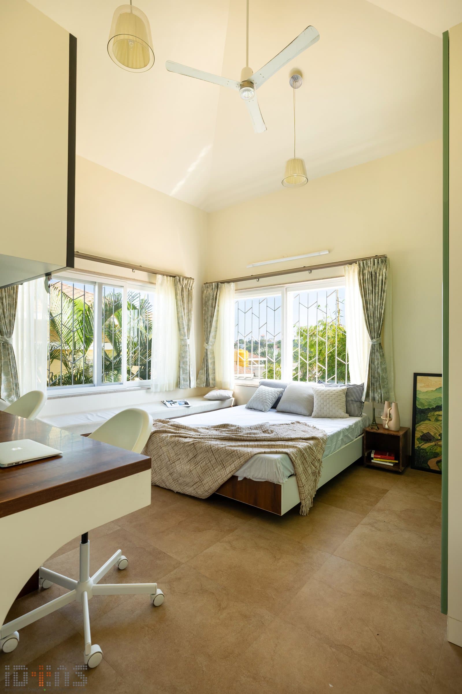 The first upper-floor bedroom: a vaulted ceiling, a window seat, and a writing desk calibrated for someone who reads, works, and looks out in equal measure