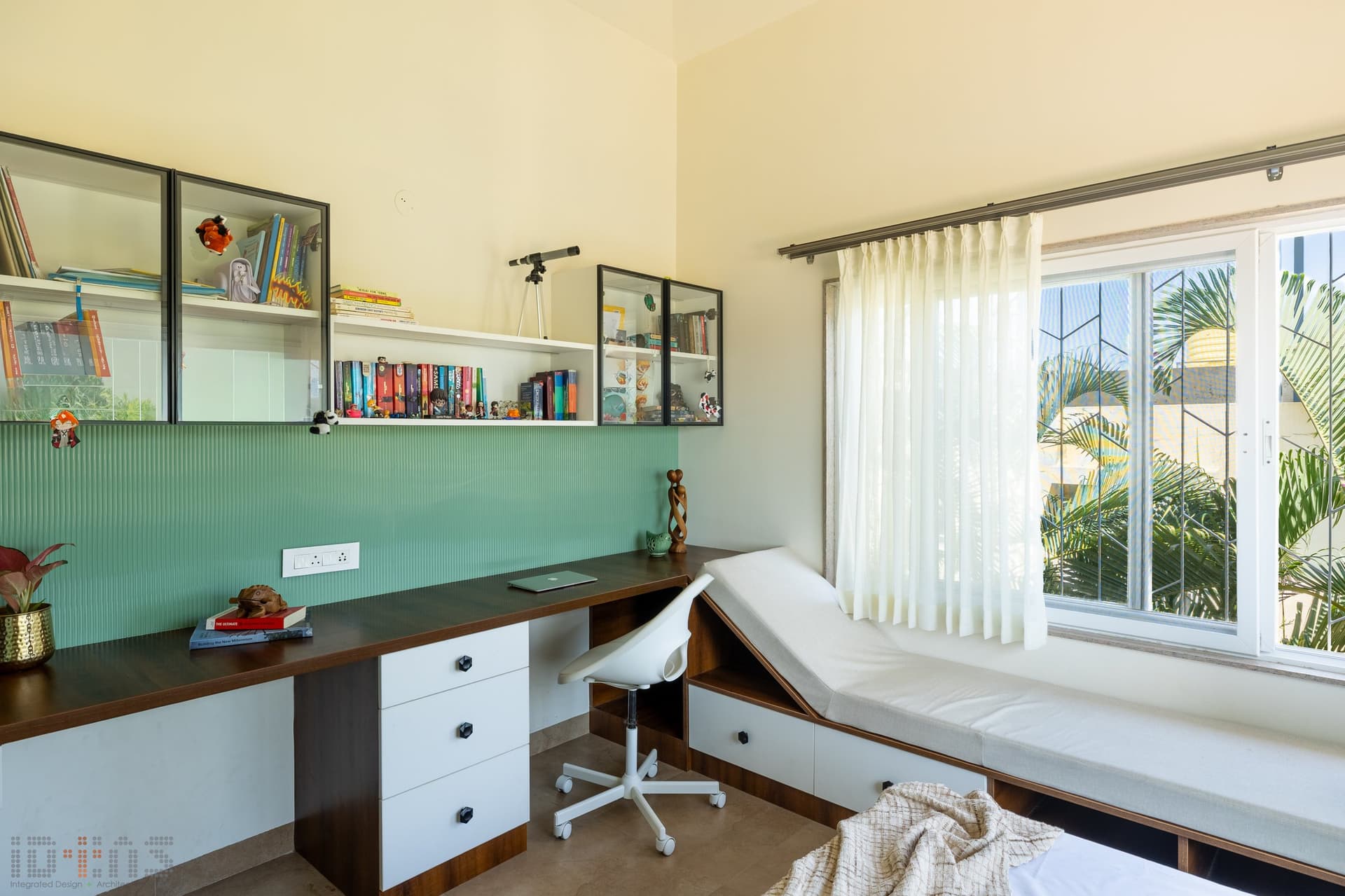 The study corner continues the green thread as a fluted backsplash above a long wood desk, with a built-in window daybed alongside