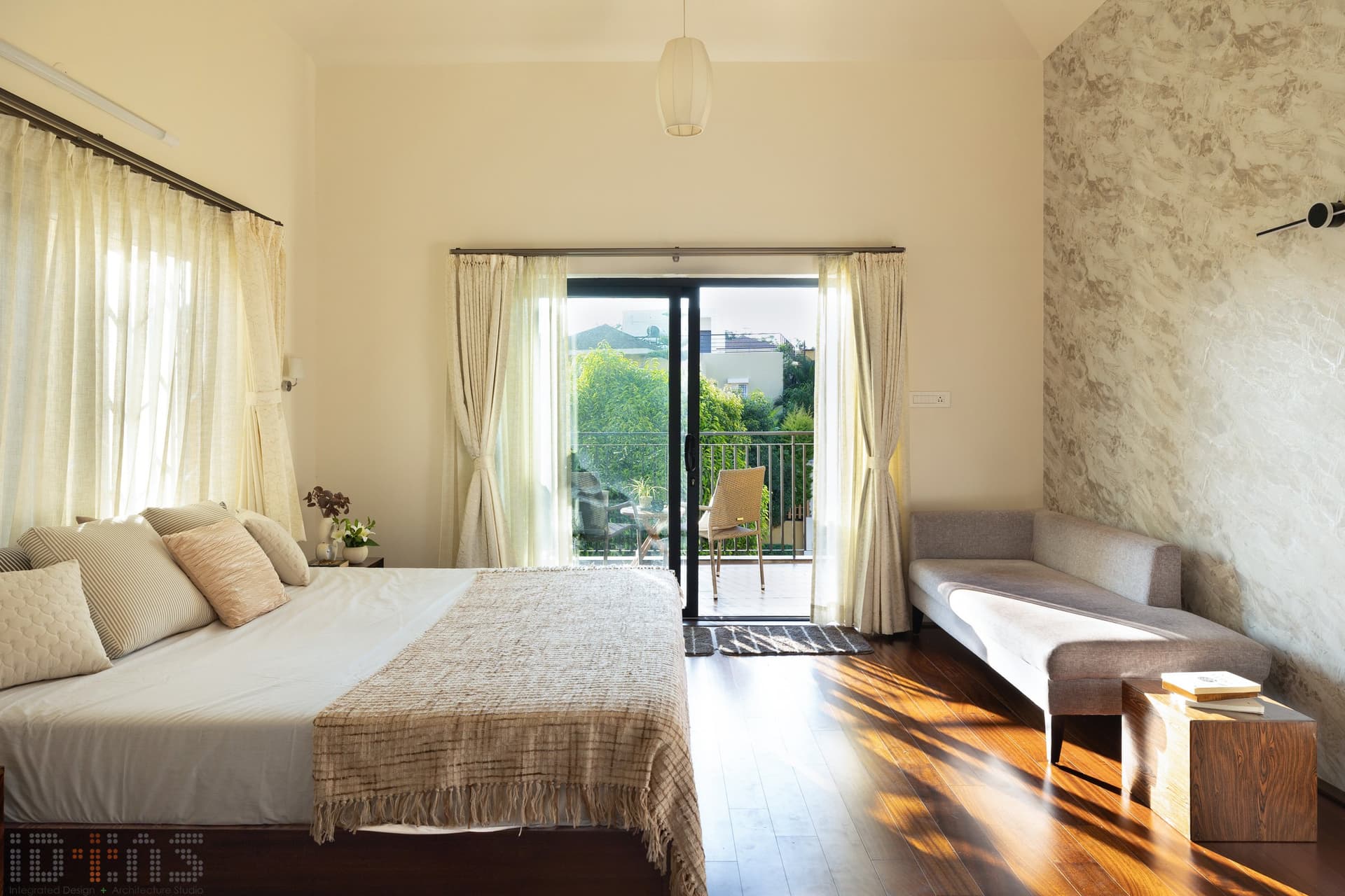 Opposite the bed, a textured plaster wall and a pale linen daybed soften the room's rectilinear bones