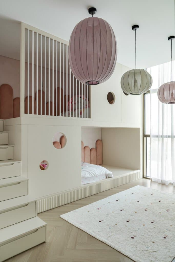 The bunk arrangement treated as architecture, with scalloped velvet headboards, porthole cutouts and lantern pendants in mauve, sage and rose
