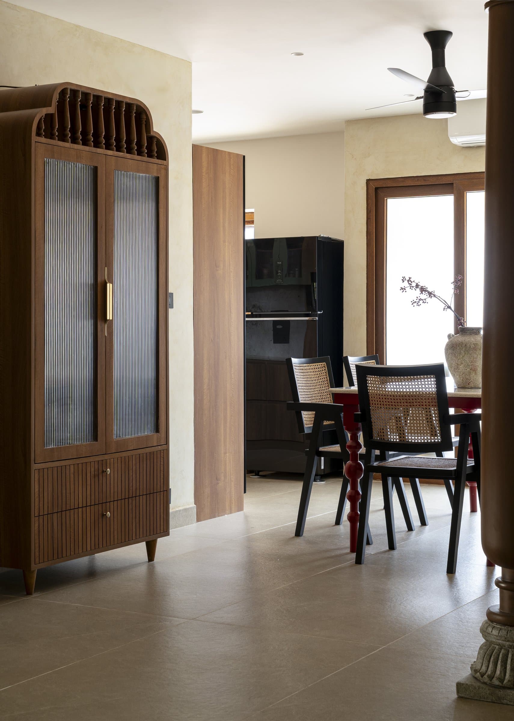 Looking from the pooja cabinet toward the dining and kitchen beyond, the lime-plastered walls carry a single warm tone across the public zones