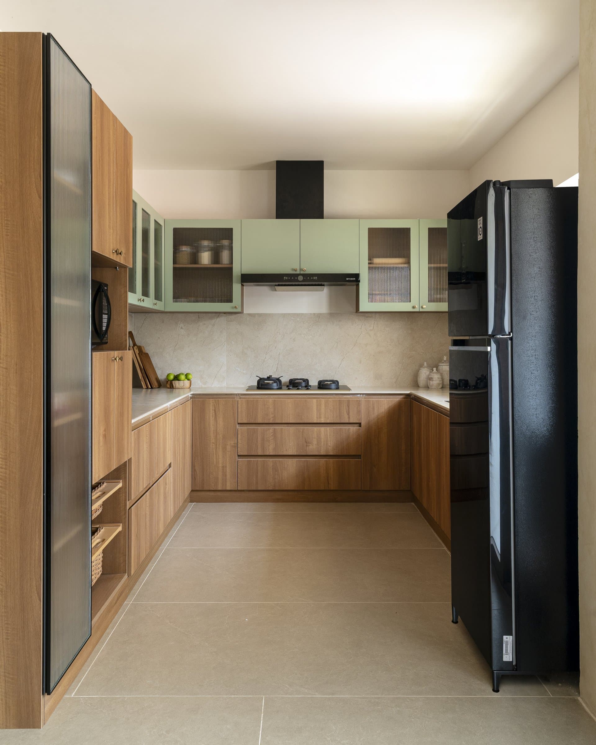 The kitchen retreats from the home's expressive register, choosing sage-green uppers and warm wood-grain lowers for quiet daily function