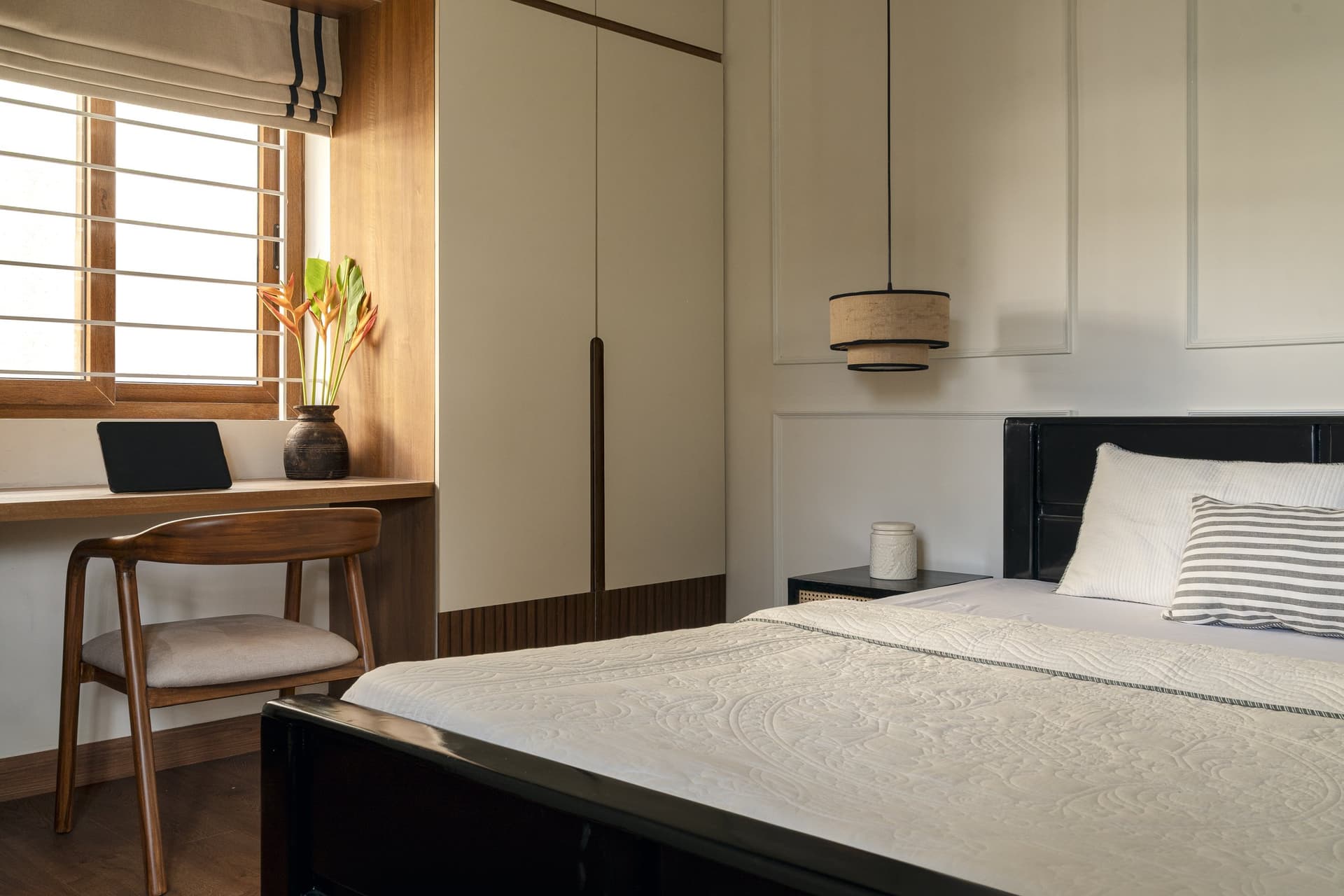 The guest bedroom, where a black-stained bed and a wainscoted wall introduce a quieter, more contemporary register