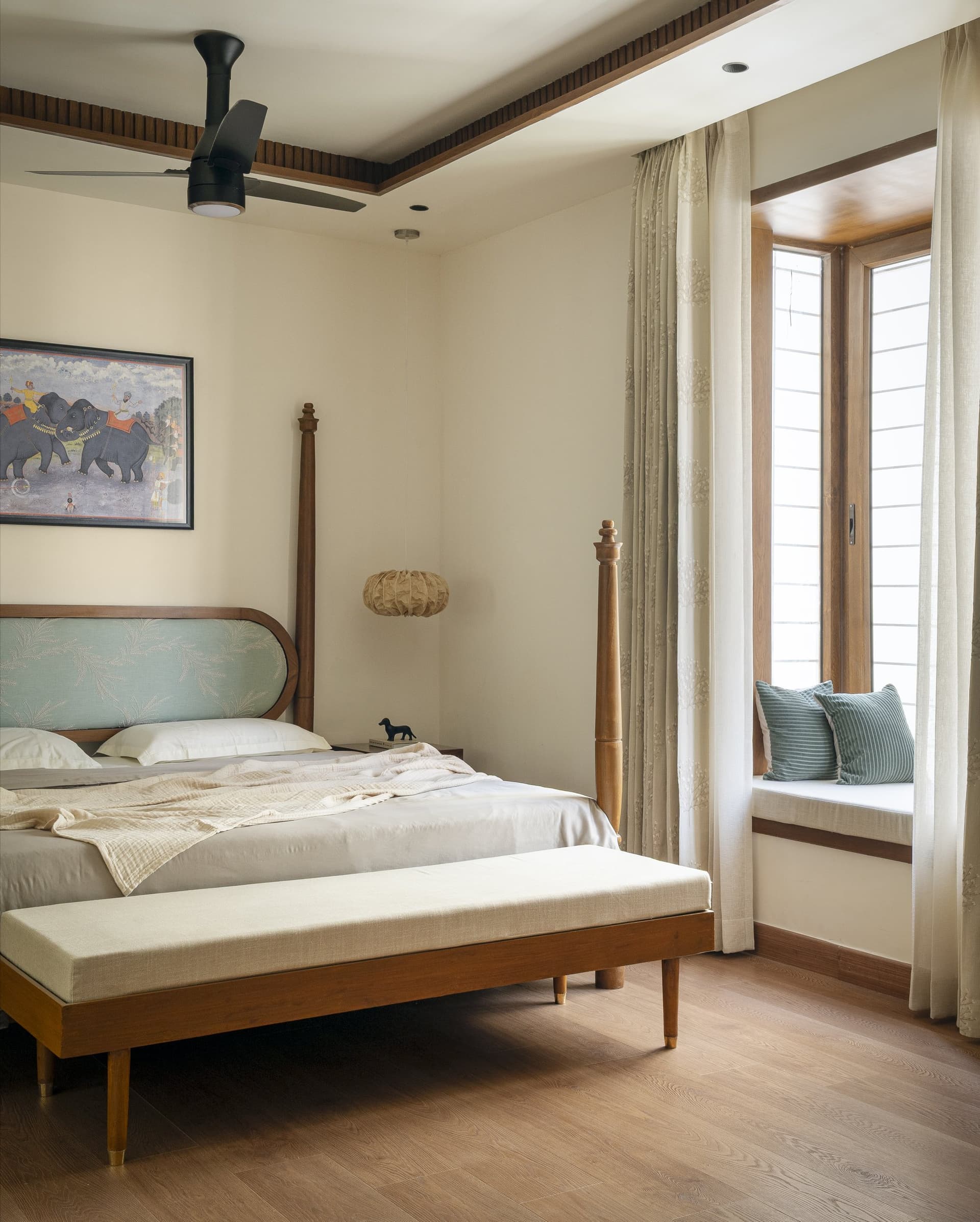 The master bedroom, with a four-poster bed in warm wood and a built-in bay window seat bathed in morning light