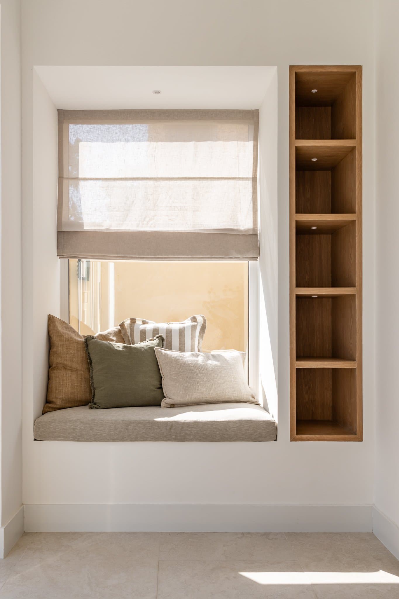 A window seat with a built-in wood niche alongside, the kind of corner that justifies its own existence