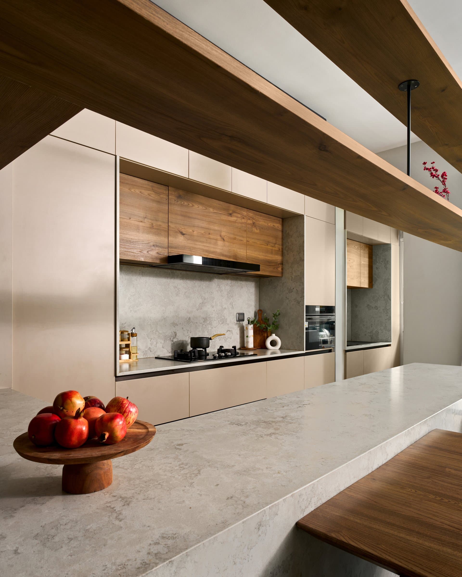 The kitchen run beneath exposed wooden ceiling beams, an exercise in dissolved storage and monochrome calm
